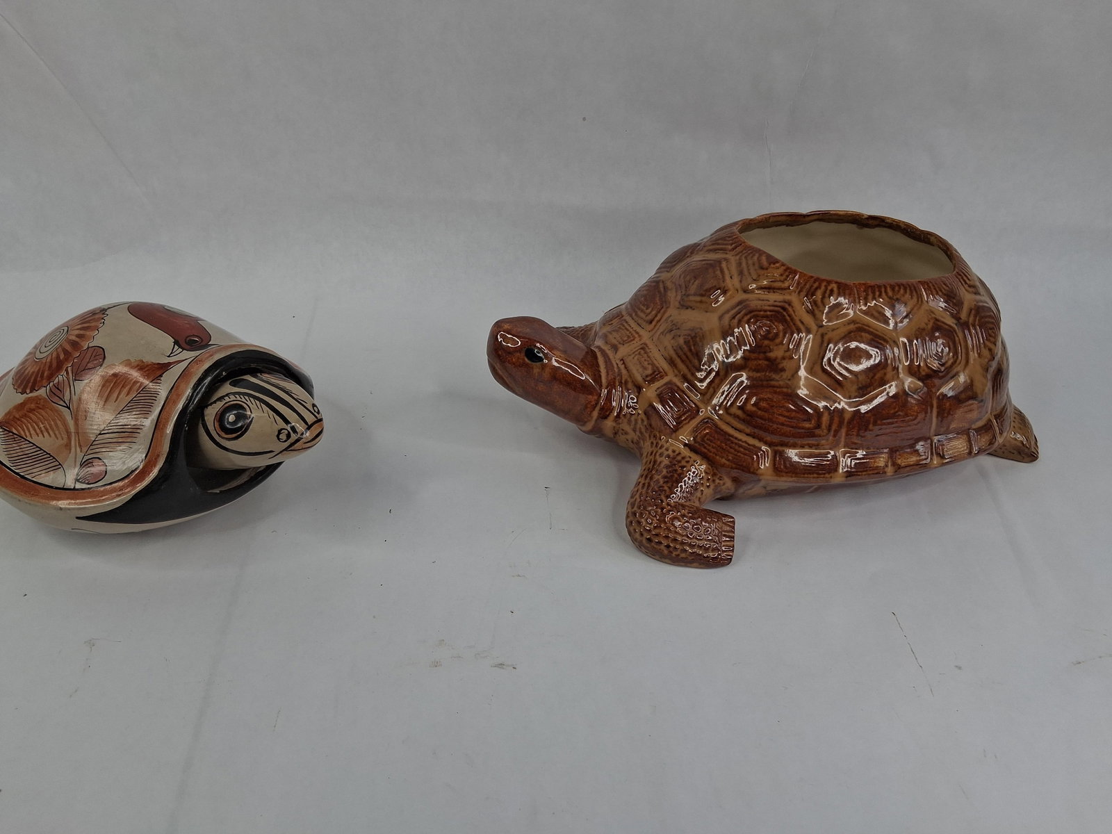 Two Ceramic Turtle Decorative Items: This lot includes two distinct ceramic pieces featuring a turtle motif. The first item is a glazed ceramic turtle planter, designed with a high-gloss variegated brown finish that accentuates the molde