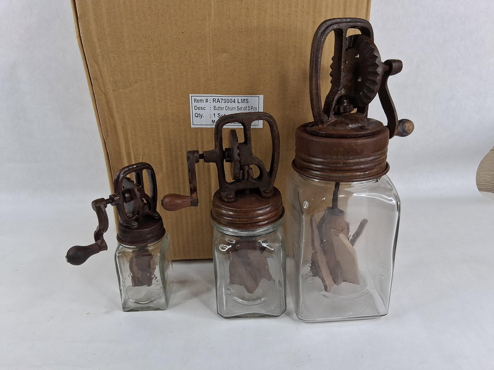 Set 3 Reproduction Dazey-Style Glass Butter Churns: This graduated set of three contemporary decorative butter churns is modeled after the antique Dazey design. Each piece features a clear, square glass jar with vertically embossed lettering reading DA