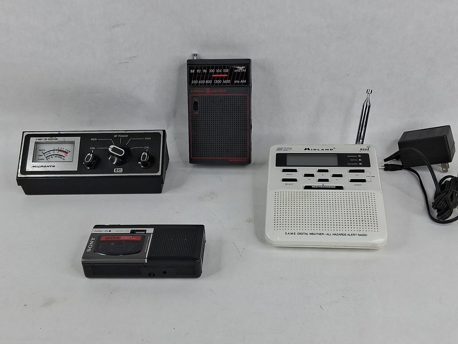 Micranta, GE, Midland & Sony Electronics: This collection of electronics features a Micranta 3-Way CB Tester, a General Electric portable radio, a Midland weather radio, and a Sony microcassette recorder. The Micranta CB Tester is equipped