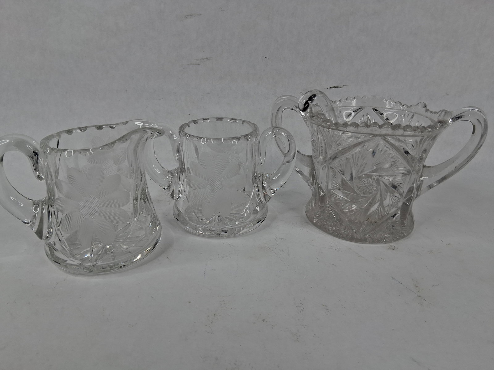 Am. Brilliant Style & EAPG Tableware w/ Ladle: An assortment of four pieces of antique and glassware. The collection features a matching creamer and two-handled open sugar bowl decorated with copper-wheel engraved daisy and floral motifs,