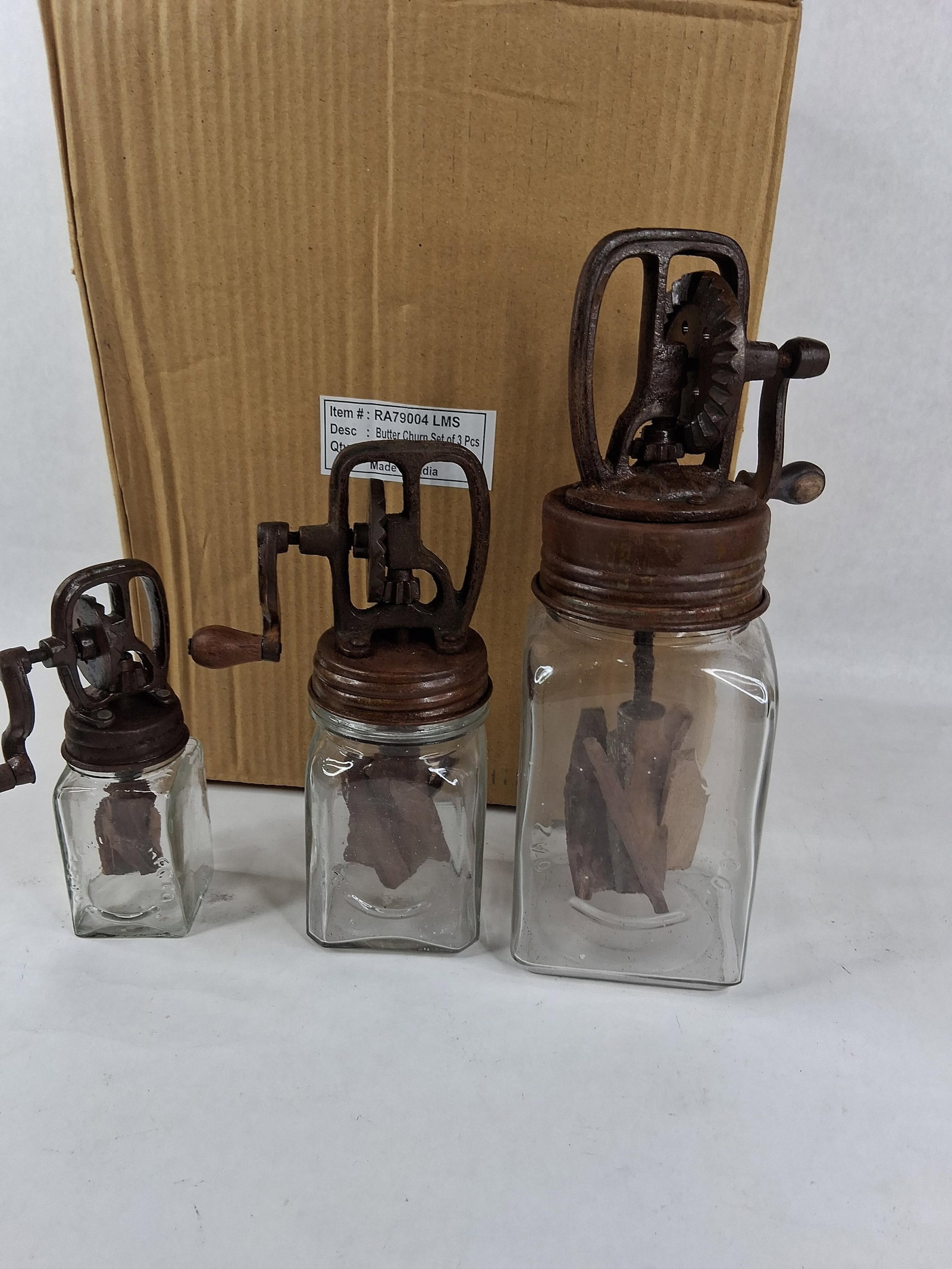 Set 3 Dazey-Style Glass & Cast Iron Butter Churns: A set of three decorative miniature butter churns designed as modern reproductions of antique models. Each piece features a clear glass jar with embossed lettering on the side reading DAZEY CHURN. The