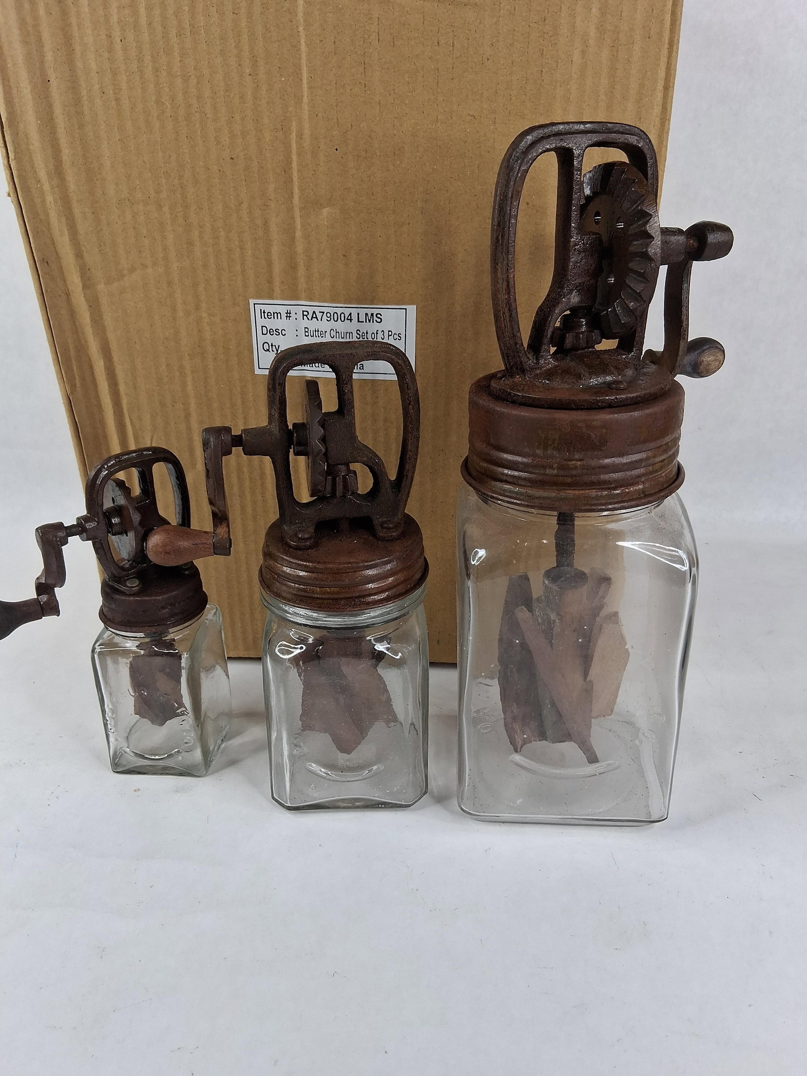 Set 3 Reproduction Dazey Style Glass Butter Churns: A set of three reproduction glass butter churns in graduated sizes, modeled after antique Dazey designs. Each unit consists of a clear, square-sided glass jar topped with a cast-metal, hand-cranked