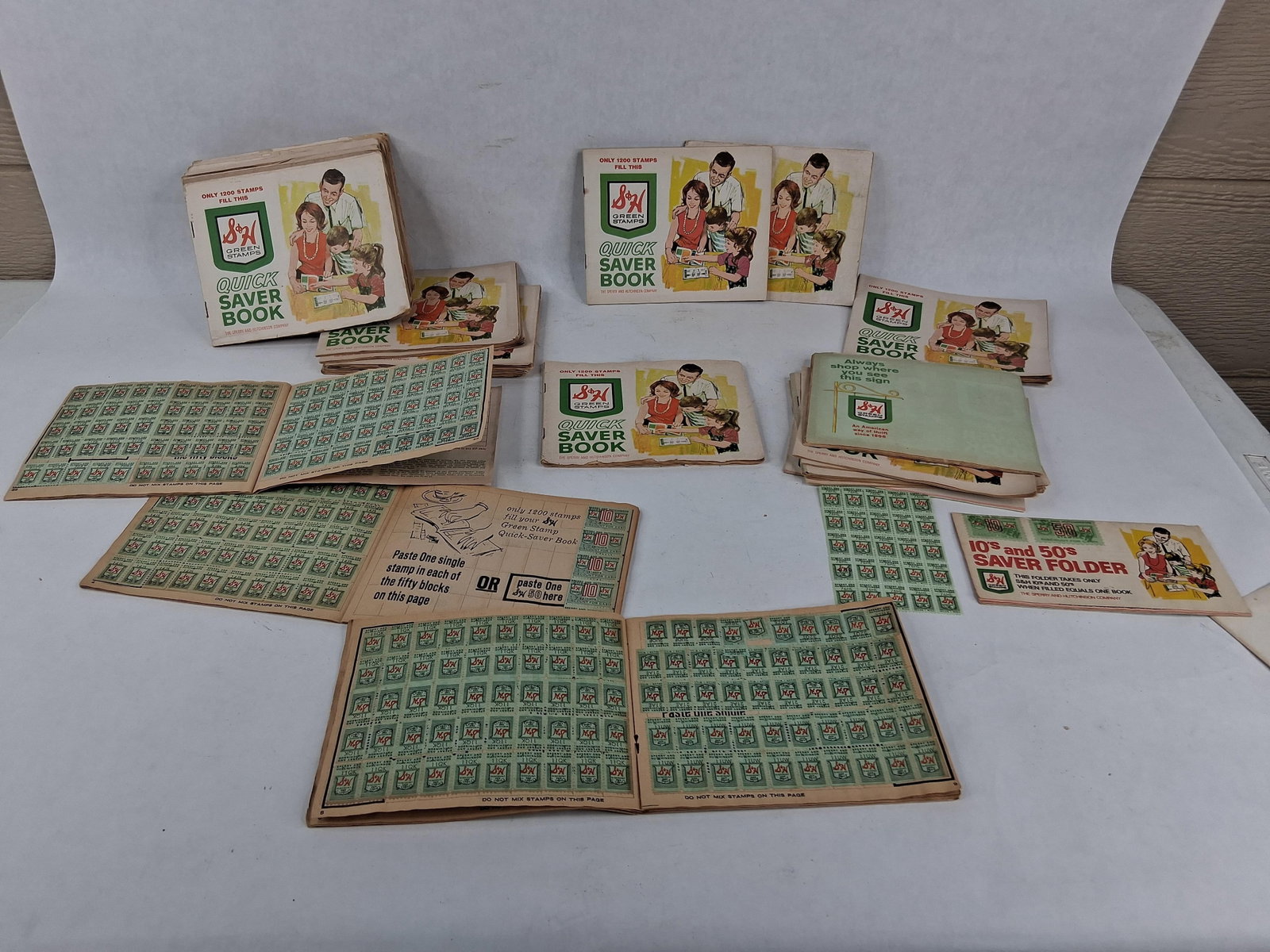 US Mid-20th C. S&H Green Stamps, Books & Sheets: A collection of consumer trading stamps issued by The Sperry and Hutchinson Company, comprising multiple Quick Saver Books, loose stamp blocks, and a 10s and 50s Saver Folder. The stamps are