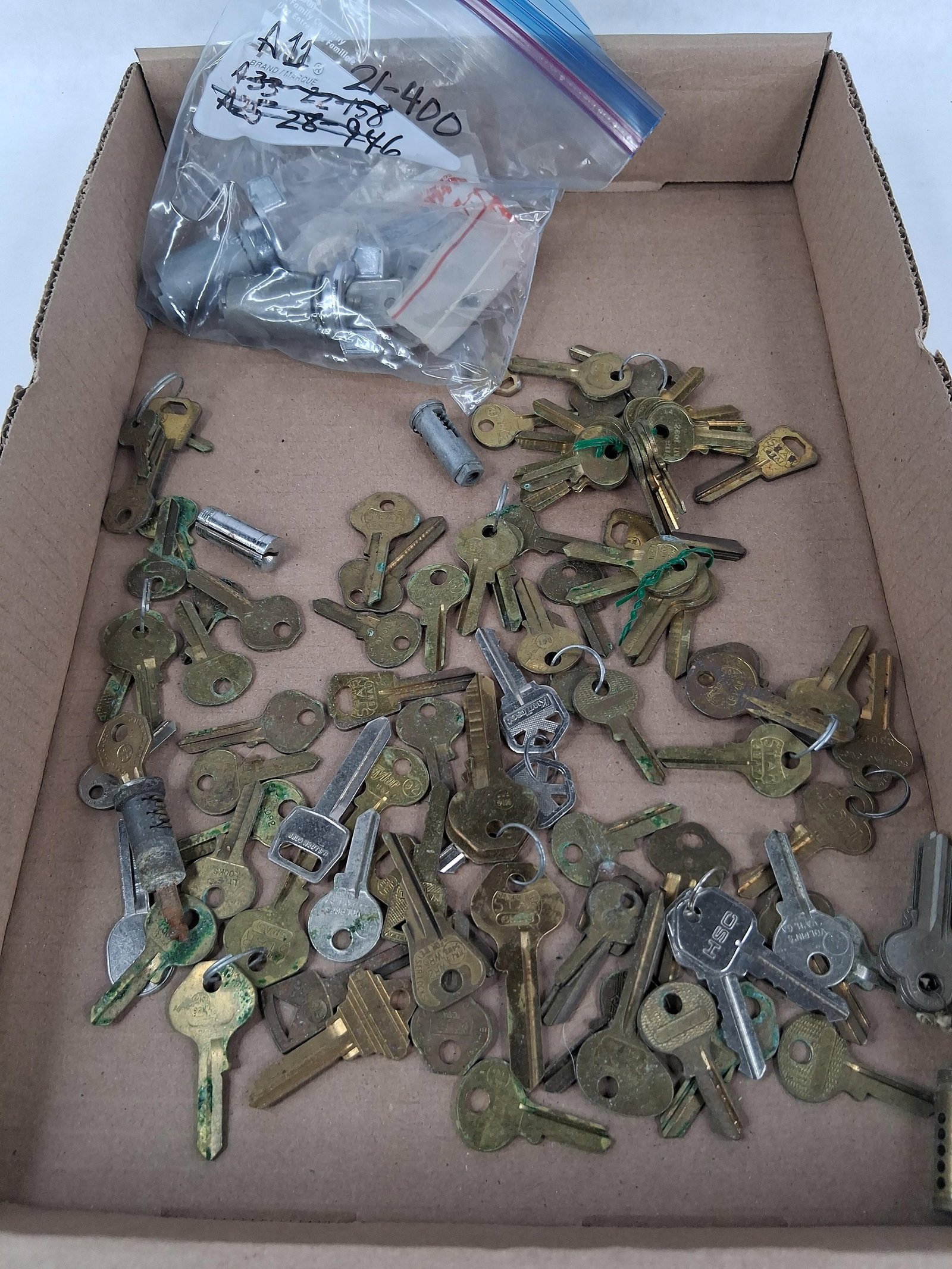 An Assortment of Keys and Lock Cylinders: This lot features an assortment of residential, commercial, and automotive keys along with several lock cylinder plugs and assemblies. The items are primarily constructed from brass, nickel-plated