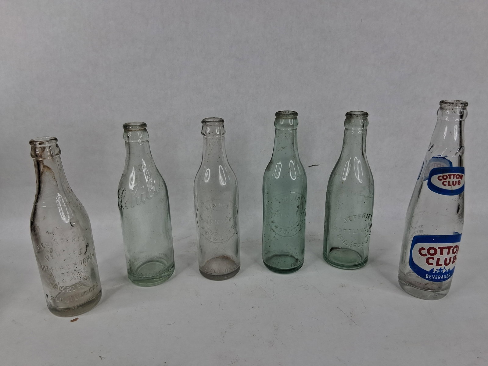 6 Ohio & Pennsylvania Glass Soda Bottles: This lot features a collection of 6 glass soda bottles from regional bottling works in Ohio and Pennsylvania. The group includes five bottles with embossed glass details and one with applied color