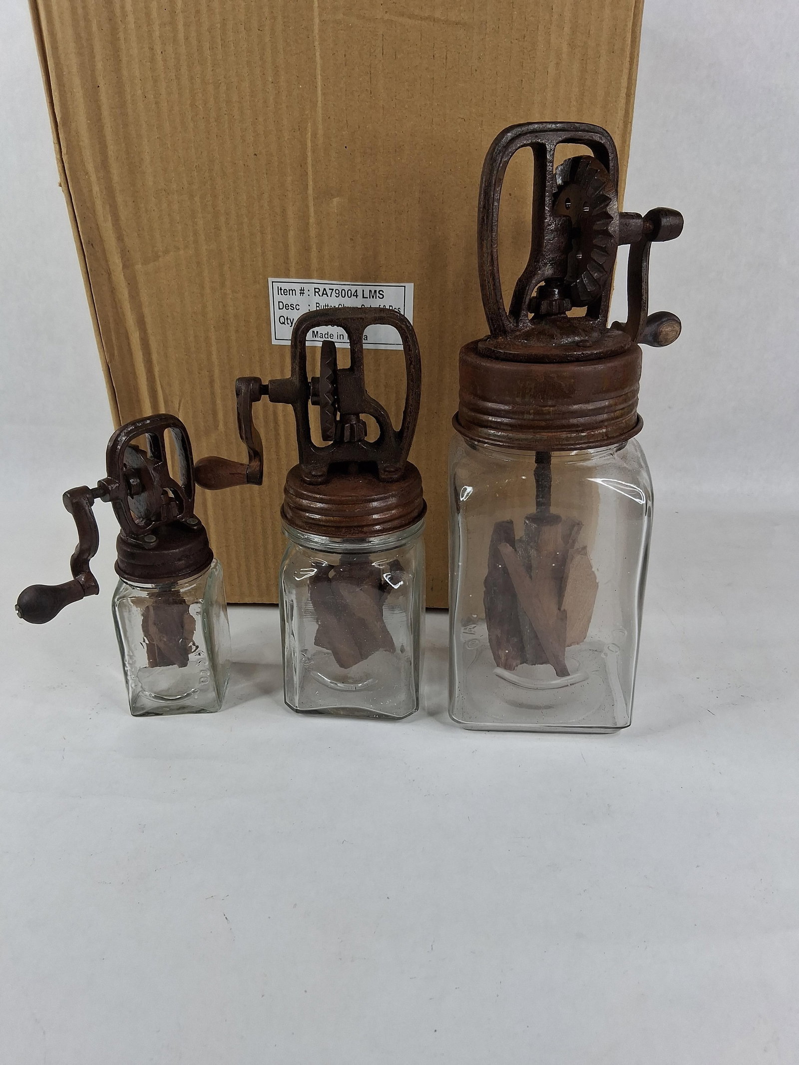 Set 3 Glass & Cast Iron Butter Churns, Dazey Style: A set of three graduated decorative reproduction butter churns, designed in the style of antique Dazey models. Each churn comprises a clear glass jar with a square base and embossed lettering; the
