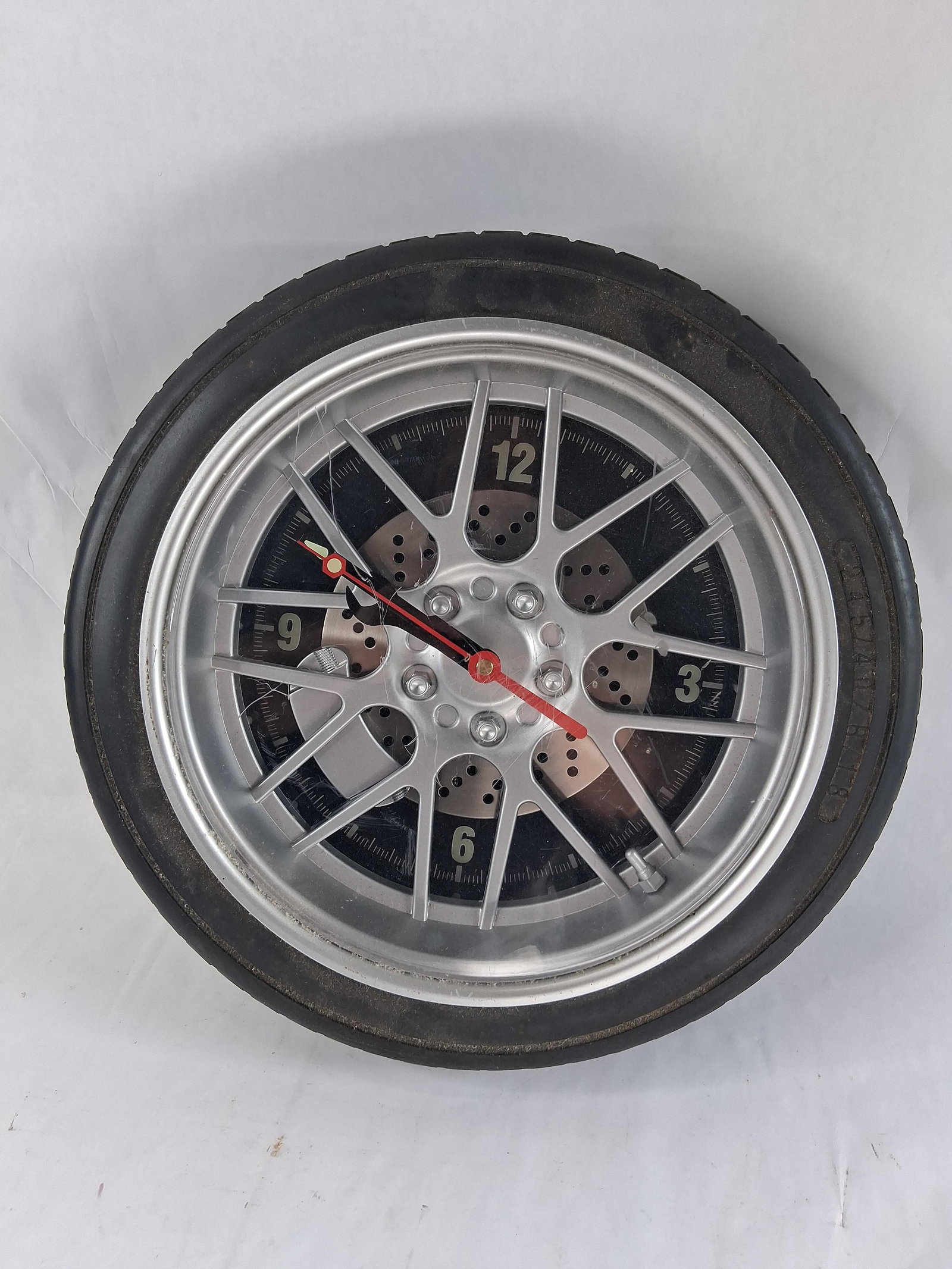Sears Automotive Wheel and Tire Novelty Wall Clock: This novelty wall clock is designed to resemble an automotive wheel and tire assembly. The outer casing is constructed of molded black plastic featuring a realistic tire tread pattern and molded