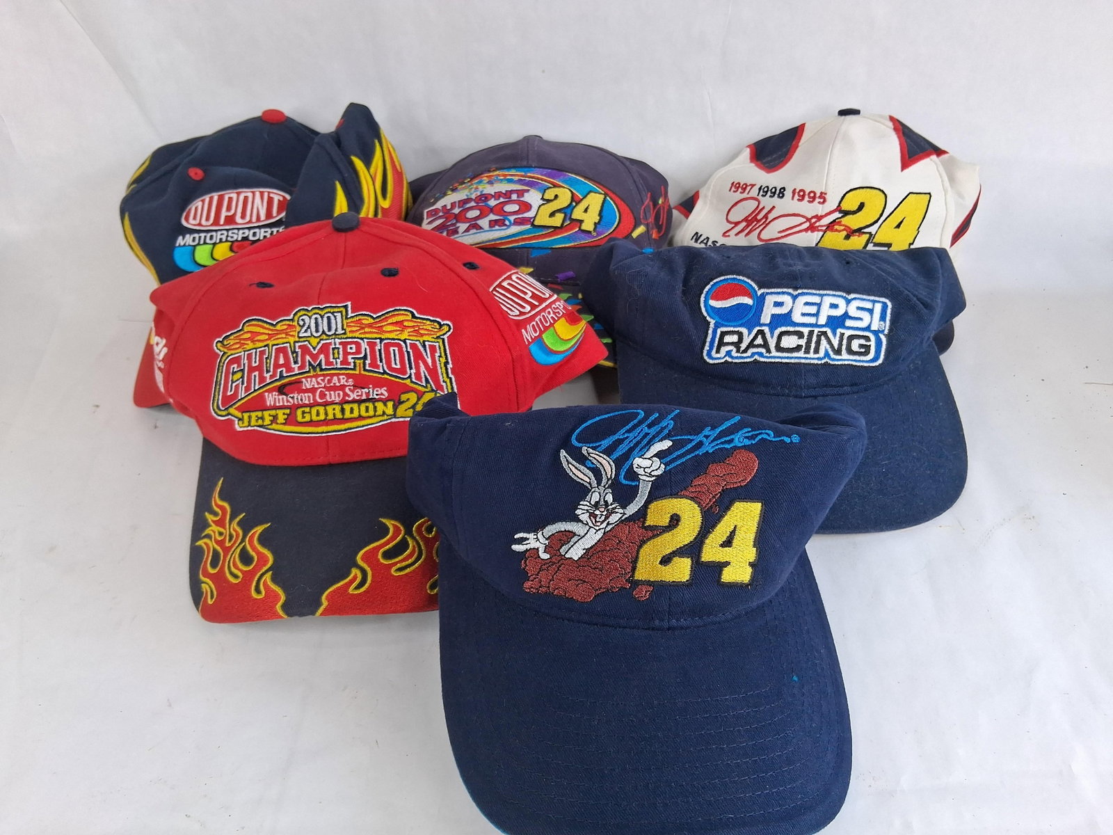 Set 8 Jeff Gordon #24 NASCAR Caps & Visor: An assortment of eight commemorative headwear items including seven baseball-style caps and one visor, all themed around NASCAR champion Jeff Gordon and the Hendrick Motorsports #24 team. The group