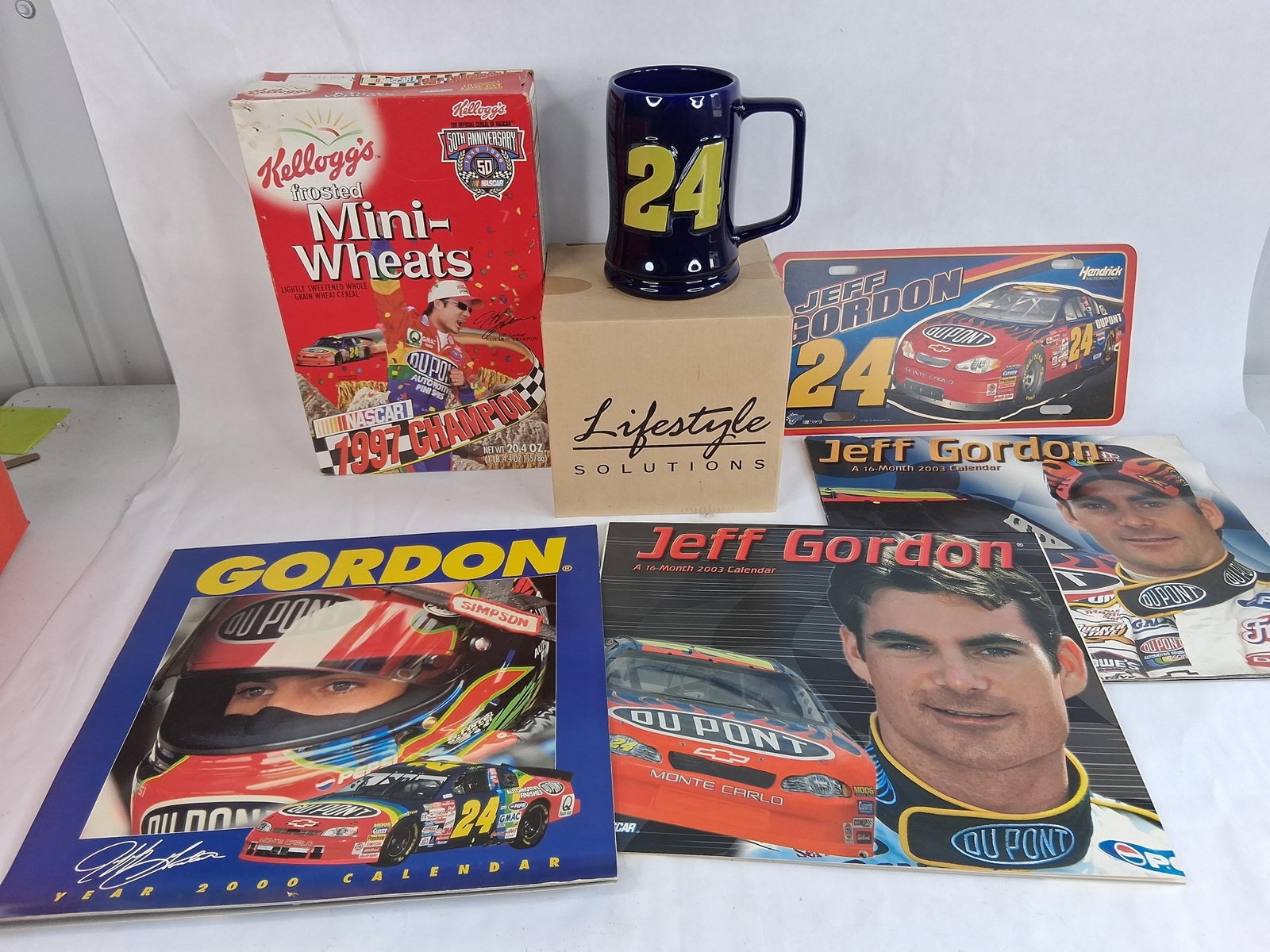 Lot of 6 Jeff Gordon NASCAR Memorabilia Items Including 1997 Kellogg's Cereal Box and Calendars: This is a collection of 6 Jeff Gordon memorabilia items related to his career in the NASCAR Winston Cup Series driving the number 24 DuPont Chevrolet for Hendrick Motorsports. The lot includes a 1997