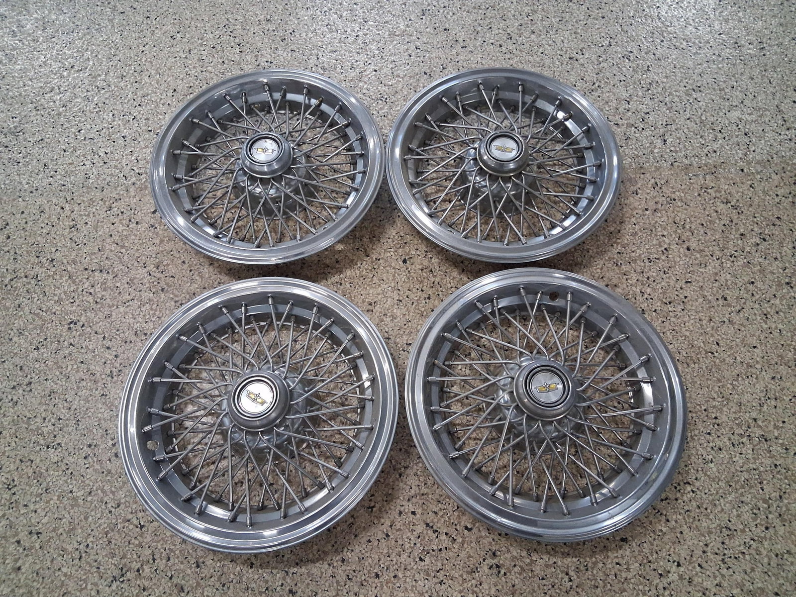 A Set of Four Chevrolet Wire Spoke Hubcaps: This set of four simulated wire wheel covers is manufactured by Chevrolet. These items were designed as factory-optional luxury trim for various full-size Chevrolet passenger cars from the late 1970s