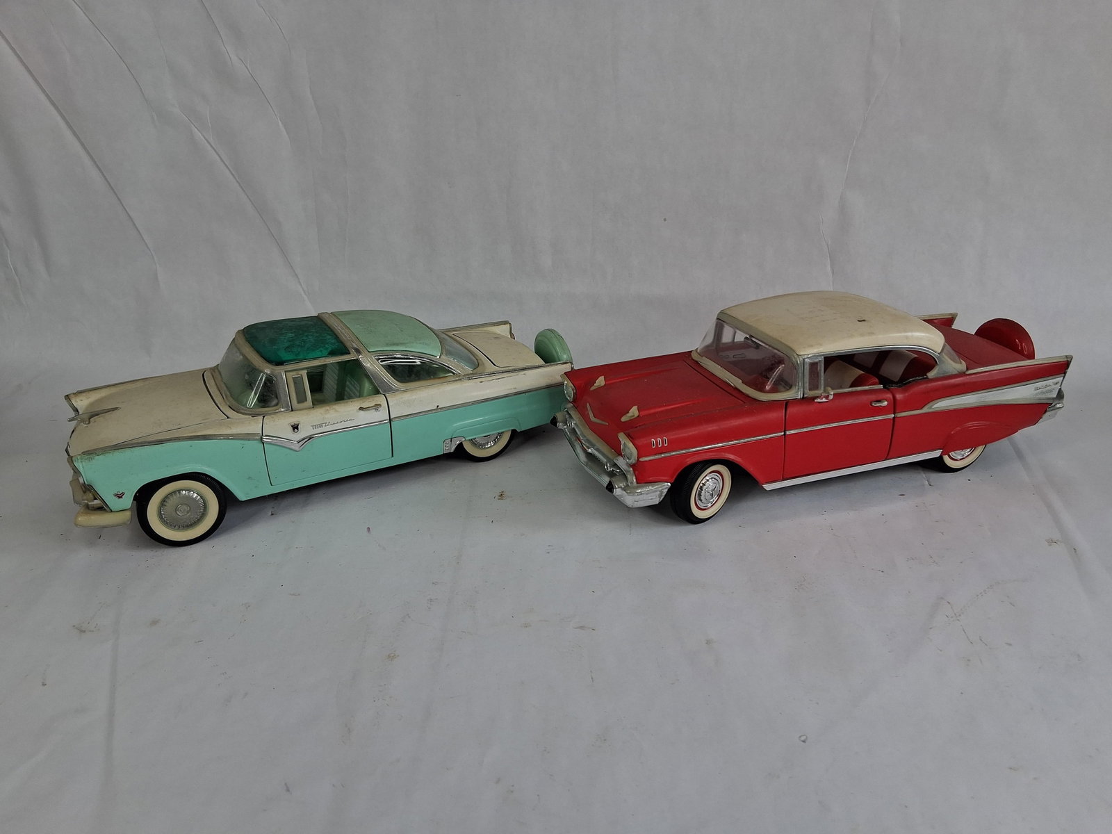 A Pair of Road Tough 1/18 Scale Model Cars: A pair of 1/18 scale model cars manufactured by Road Tough, featuring classic American automotive designs from the mid-1950s. The first model is a 1955 Ford Fairlane Crown Victoria, finished in a