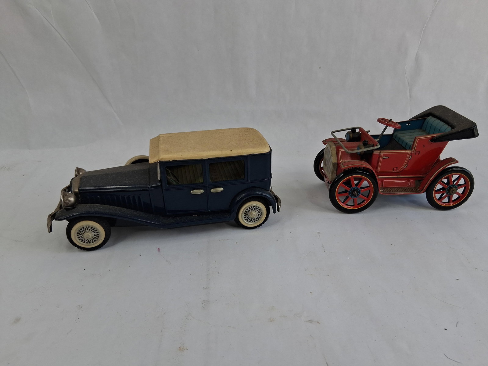 Pair Japanese Tinplate Modern Toys & Lincoln Cars: This lot features a pair of lithographed tinplate toy vehicles manufactured in Japan. The first vehicle is an open-top veteran-style car produced by Modern Toys (Masudaya). The car is finished in red