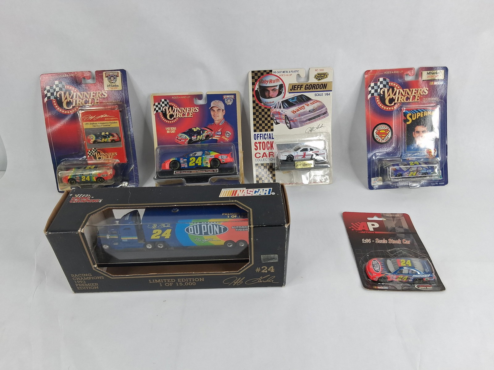 6 Jeff Gordon NASCAR Die-Cast Cars & Transporter: This group consists of six Jeff Gordon themed NASCAR die-cast collectibles manufactured by brands including Winner's Circle, Racing Champions, Road Champs, and Action Performance. The collection