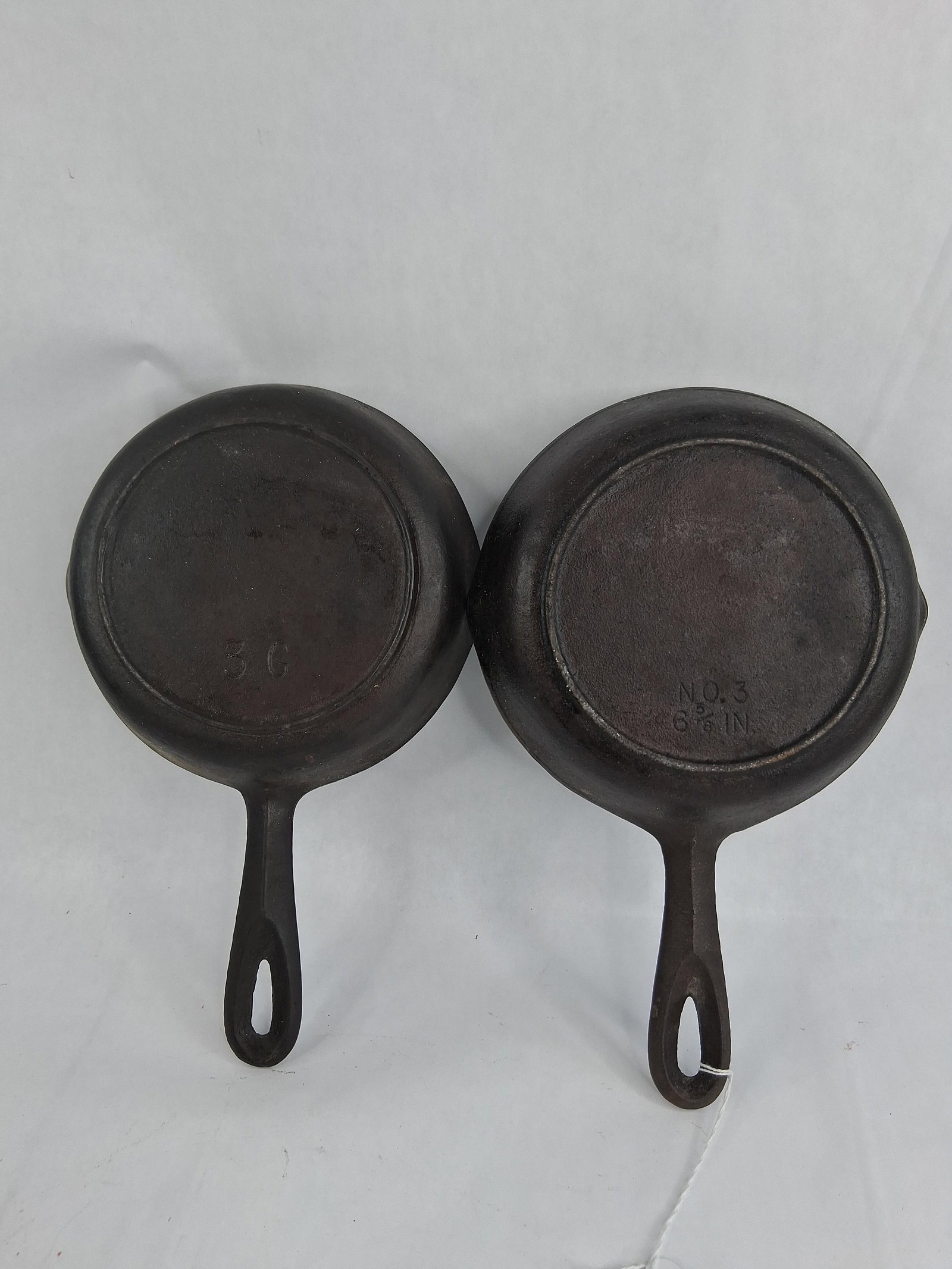 Pair Lodge & Birmingham Stove Cast Iron Skillets: This lot features two American-made cast iron skillets, both size No. 3. The first skillet is attributed to the Lodge Manufacturing Co. and features a single-notch heat ring at the twelve o'clock posi
