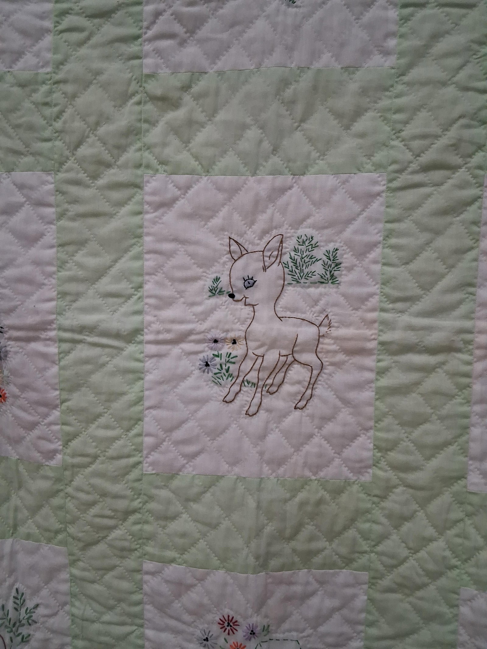 Mid-Century Hand Embroidered Animal Motif Quilt: 37x46 This nursery quilt features nine white rectangular panels, each decorated with a different hand-embroidered animal motif. The motifs include a chick, a lamb, a rabbit, a kitten, a deer, an