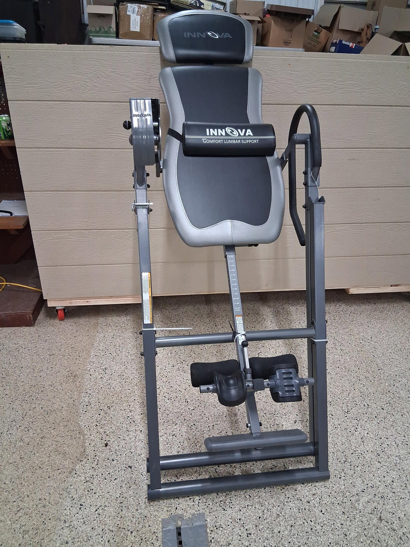 Innova Inversion Table w/ Lumbar Support: This is an Innova brand inversion table, consistent with model ITX9900. It features a gray and black padded backrest and an adjustable headrest. A removable Comfort Lumbar Support cushion is secured
