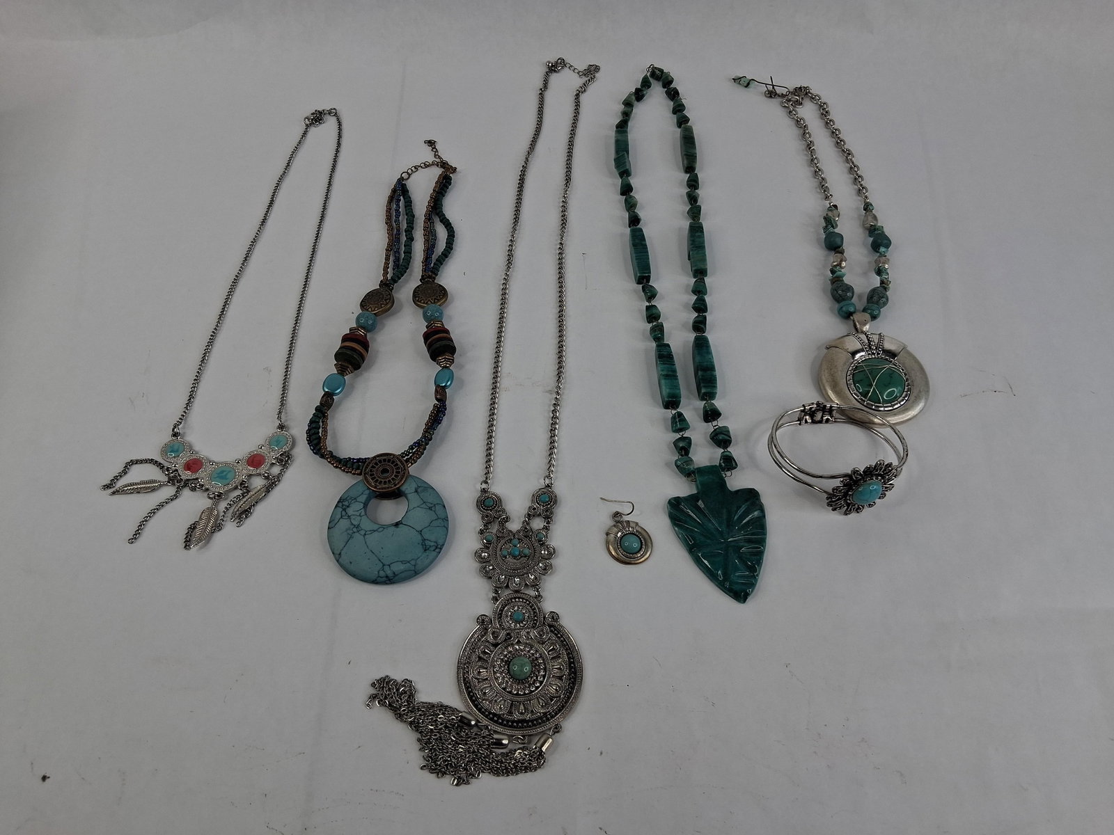 Southwestern & Boho Costume Jewelry & Earring: This lot consists of six pieces of costume jewelry and one single earring, designed in Southwestern and Boho-chic styles. The collection features a silver-tone bib necklace on a curb chain with five c
