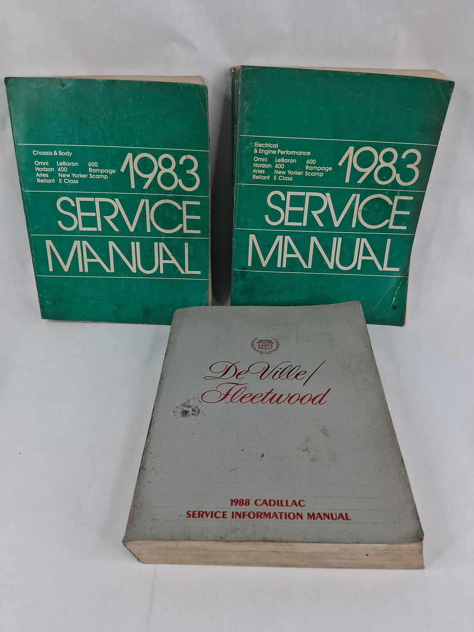 4 1983 Chrysler & 1988 Cadillac Service Manuals: This lot contains four automotive shop service manuals, consisting of a three-volume set for 1983 Chrysler Corporation vehicles and a single volume for the 1988 Cadillac De Ville and Fleetwood