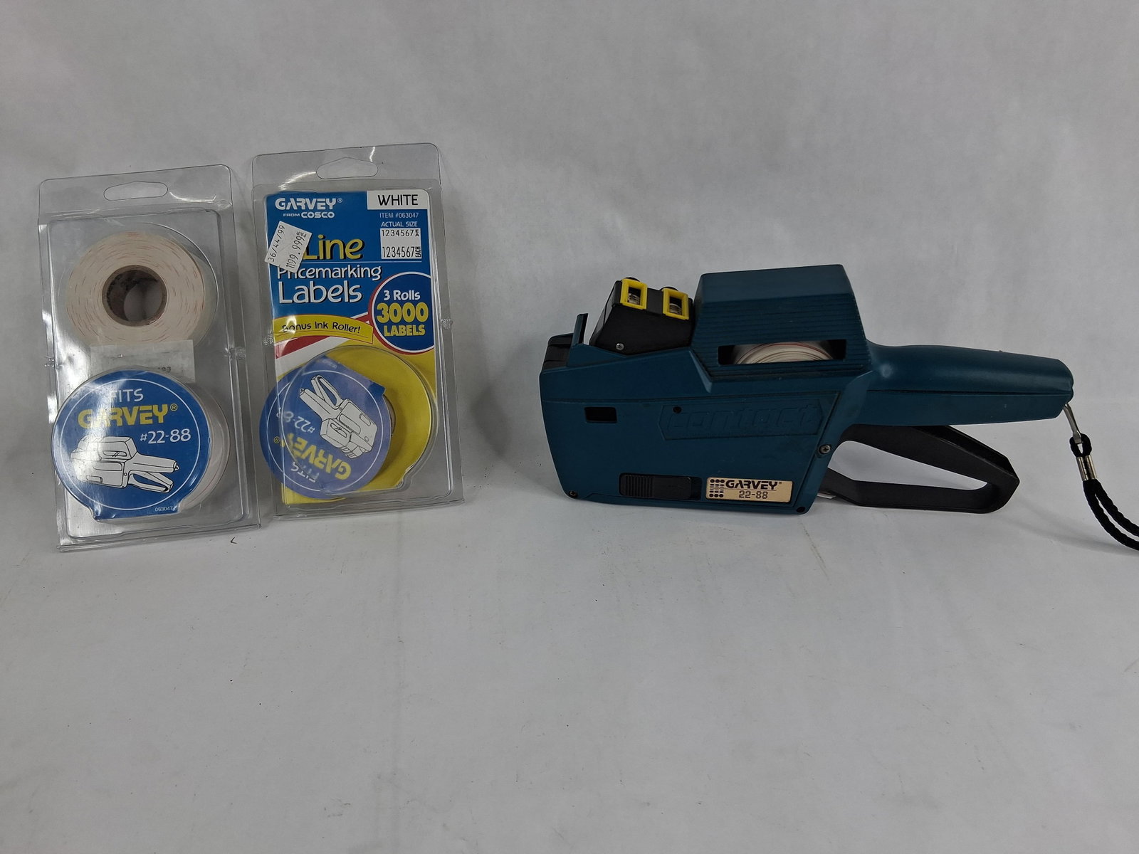 Garvey 22-88 Contact Two-Line Price Gun & Labels: A collection of retail marking supplies featuring a Garvey 22-88 Contact two-line handheld price gun. The device is manufactured with a teal-colored plastic housing, a black plastic ergonomic handle,