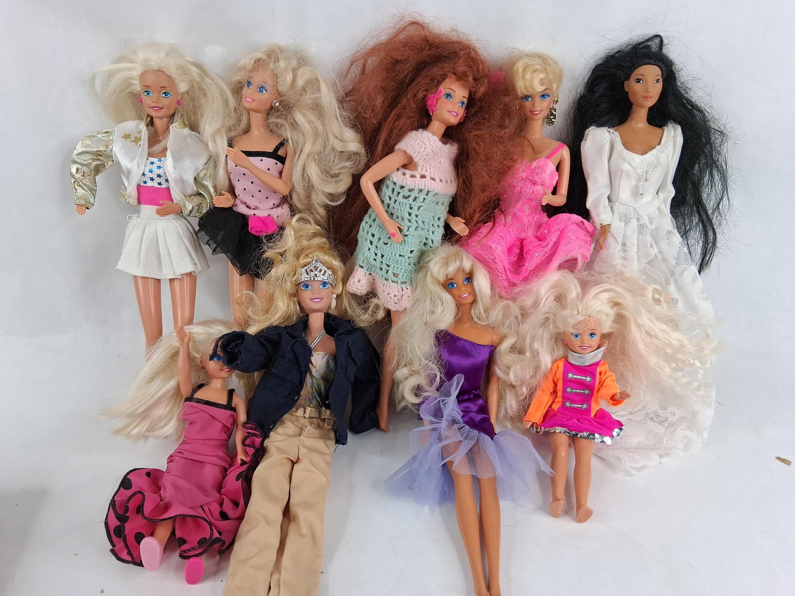 9 Mattel Barbie & Friends Fashion Dolls: A collection of nine fashion dolls manufactured by Mattel. The group includes eight standard-sized fashion dolls and one small child-sized doll. The dolls are constructed from molded vinyl and