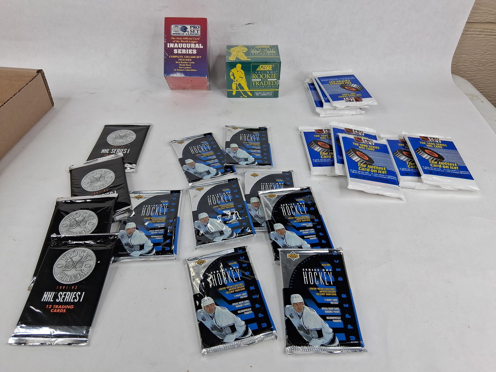 Early 1990s Sealed Sports Card Sets & Hockey Packs: This assortment features a collection of sports trading cards in their original, unopened factory packaging, primarily focusing on early 1990s hockey with one football set included. The collection