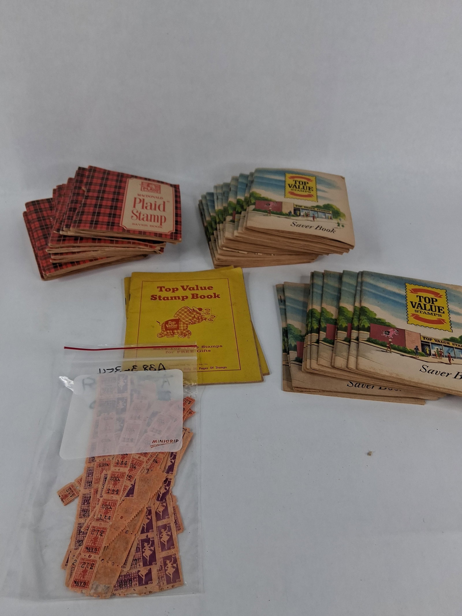 Top Value & MacDonald Plaid Stamp Collection: A collection of approximately 35 to 40 mid-20th-century retail trading stamp saver books and a quantity of loose gummed stamps representative of popular American consumer loyalty programs. The lot
