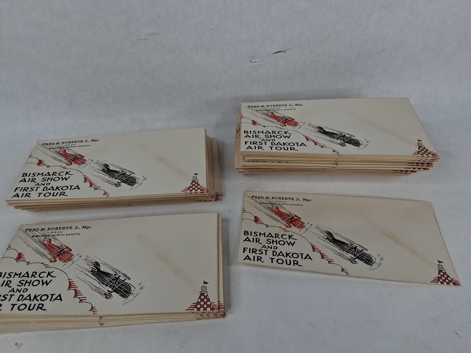 Bismarck Air Show & Dakota Air Envelopes, c. 1928: This lot comprises four substantial stacks of original, unused business-style paper envelopes promoting the Bismarck Air Show and First Dakota Air Tour. The front of each envelope features a dynamic