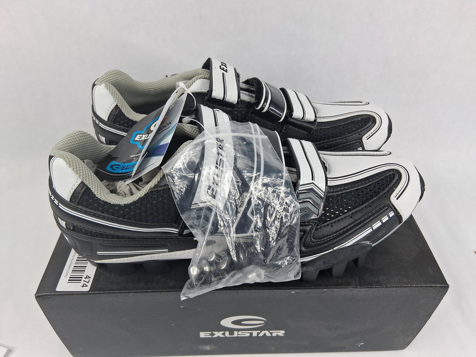 Pair Exustar E-SM341 MTB Cycling Shoes: A pair of Exustar model E-SM341 mountain bike (MTB) cycling shoes. The shoes are designed with a black and white synthetic upper featuring gray mesh panels for breathability. The closure system