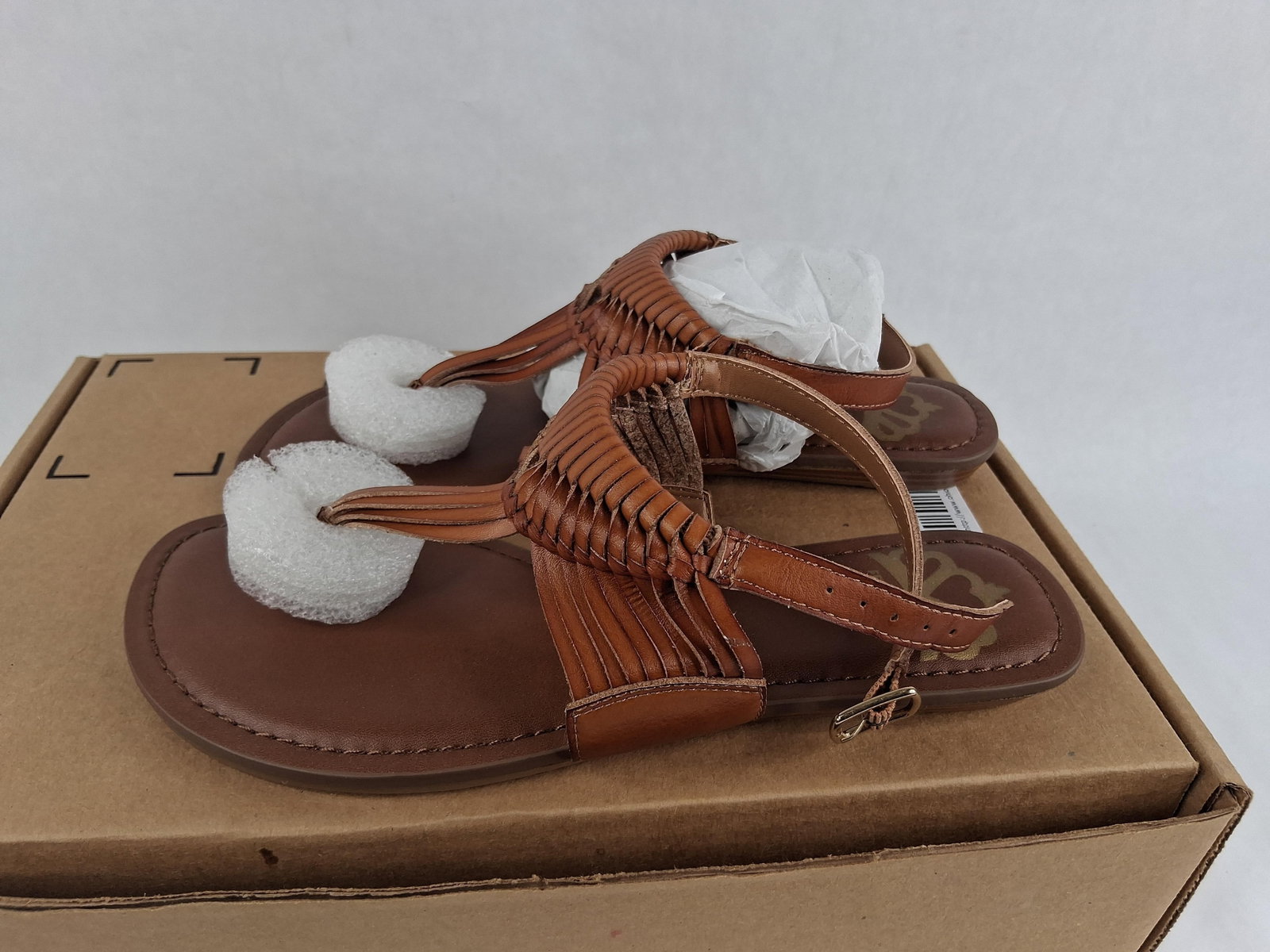 Pair Fergialicious Sadey Woven Thong Sandals: A pair of Fergialicious by Fergie Sadey model women's flat thong sandals in a brown colorway. The design features a decorative woven macram?-style upper in a cage pattern that leads to a thong toe