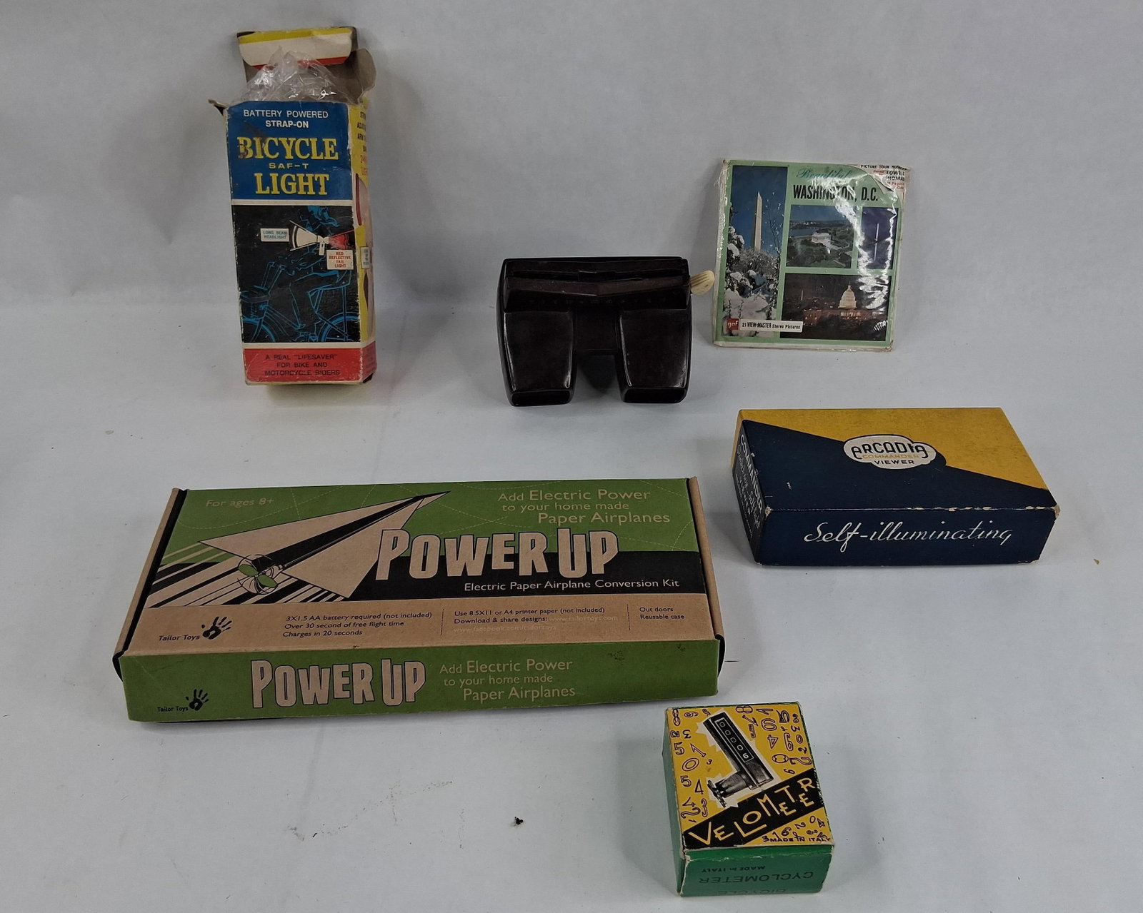 A Collection of Bicycle Accessories, Stereoscopic Viewers, and Electric Toy Kit in Original: This collection consists of several toy and utility items, most of which are housed in their original retail packaging. The lot includes a View-Master Model E stereoscopic viewer made of dark brown
