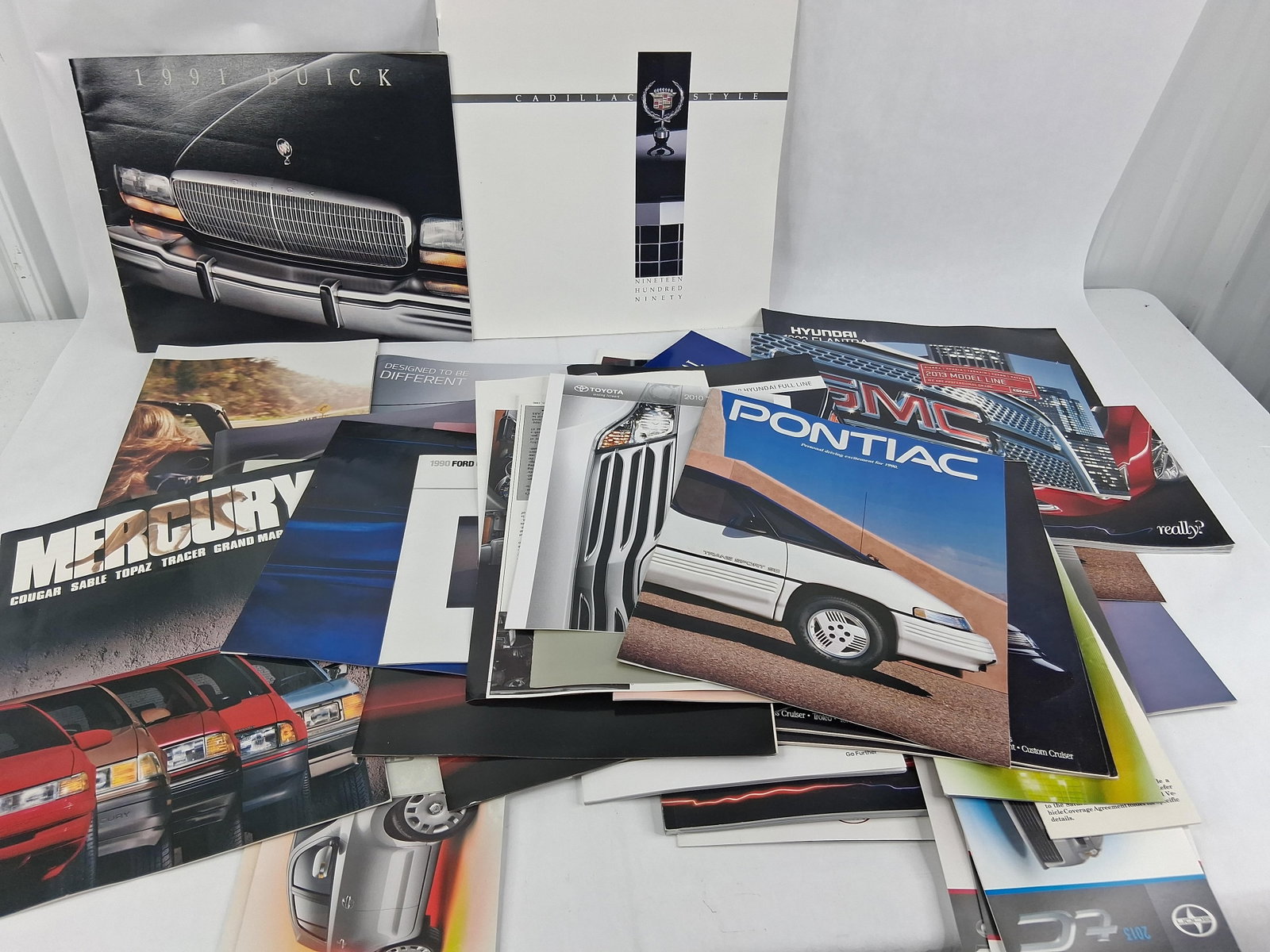 Domestic & Import Auto Sales Brochures 1990-2013: This is a collection of original automotive sales brochures and marketing catalogs from various domestic and international manufacturers, primarily representing two distinct eras: the early 1990s and