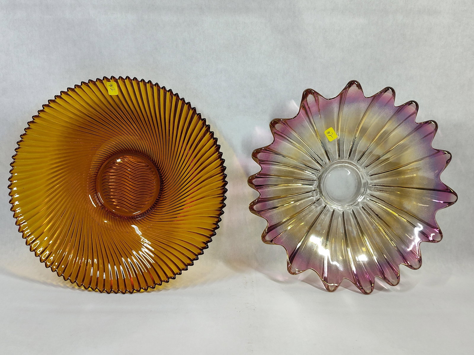 Mid-Century Pressed Glass Amber & Iridescent Bowls: This lot consists of two decorative pressed glass bowls from the mid-20th century. The first item is a large, shallow footed bowl crafted from transparent amber glass. It features a continuous spiral