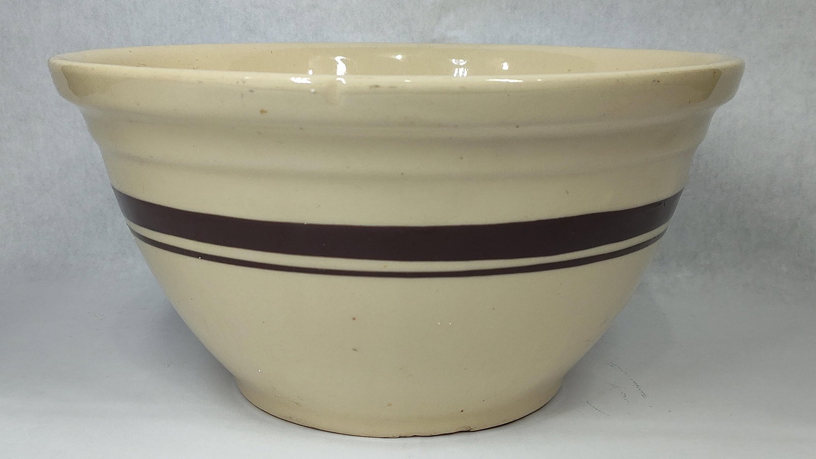 American Oven Ware Mixing Bowl w/ Brown Bands: A vintage American utilitarian mixing bowl, crafted from cream-colored stoneware and often attributed to McCoy Pottery based on the mark style. The bowl features a classic flared form with a tapered b