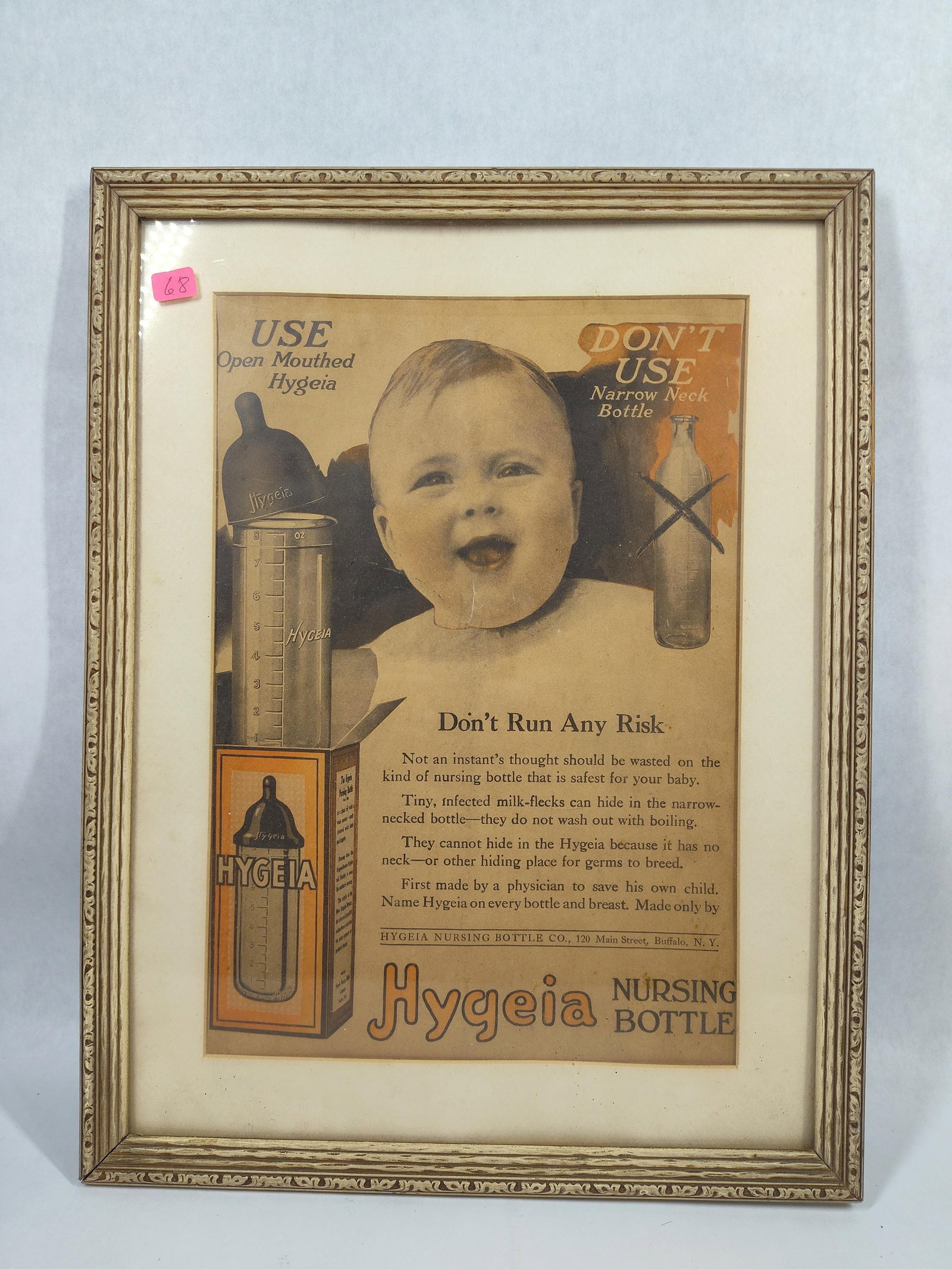 Early 20th C. Hygeia Nursing Bottle Advertisement: A framed vintage paper advertisement for the Hygeia Nursing Bottle Company of Buffalo, New York. The advertisement features a central black and white photograph of a smiling infant, flanked by