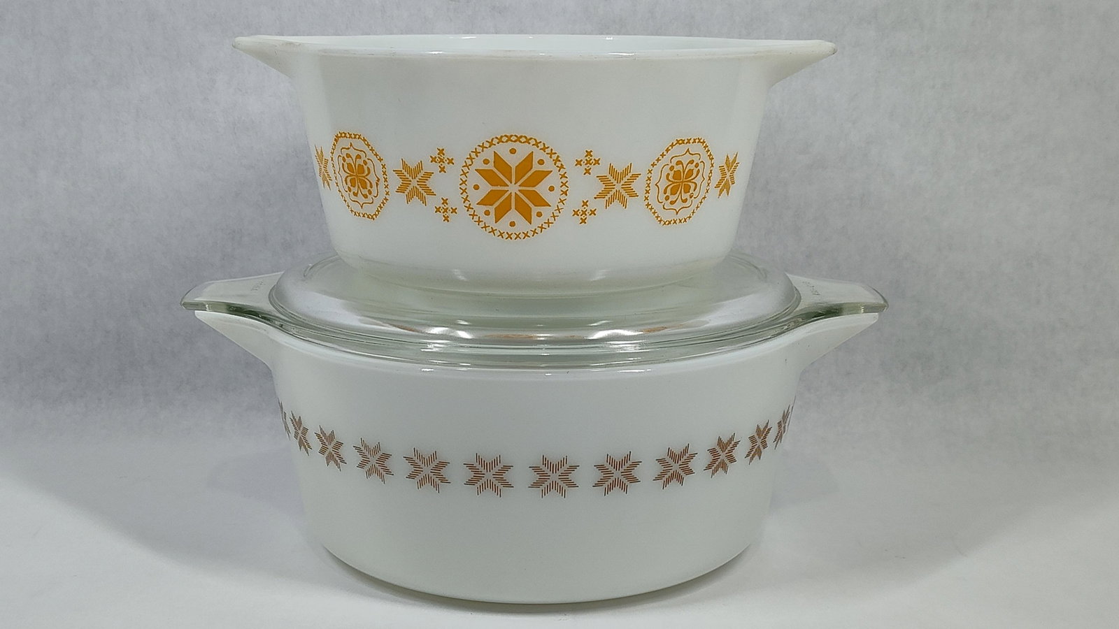 Two Pyrex Opal Glass Casserole Dishes in Snowflake and Town and Country Patterns: This lot features two Pyrex opal glass Cinderella casserole dishes. The smaller dish, model 473-B, displays the Snowflake pattern in yellow, consisting of large geometric snowflakes in dotted circles