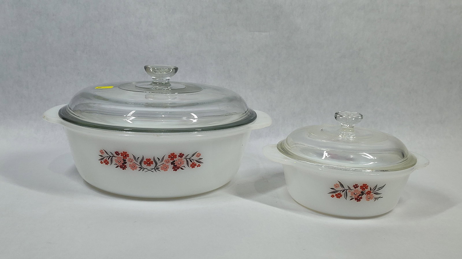 Pair Vtg Fire-King Primrose Milk Glass Casseroles: This pair of vintage casserole dishes is manufactured by Fire-King, a brand of the Anchor Hocking Glass Corporation. The dishes are constructed from opaque white milk glass and feature the Primrose
