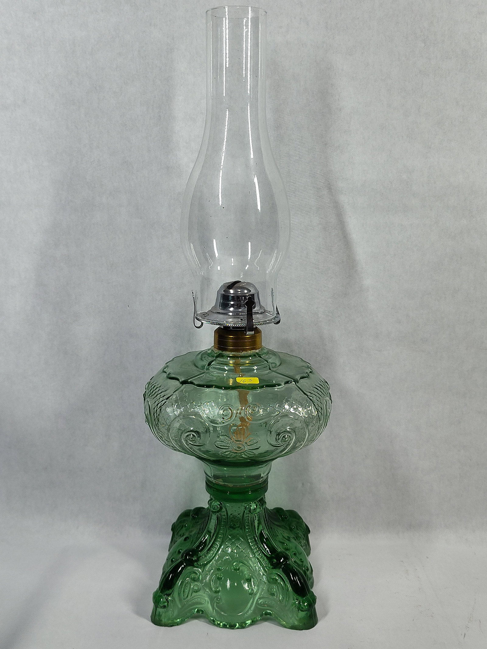 Green Princess Feather Pressed Glass Oil Lamp: This is a vintage pressed glass oil lamp in a translucent green color. The font is decorated in the Princess Feather pattern, a design originating in the Victorian era, featuring a central floral