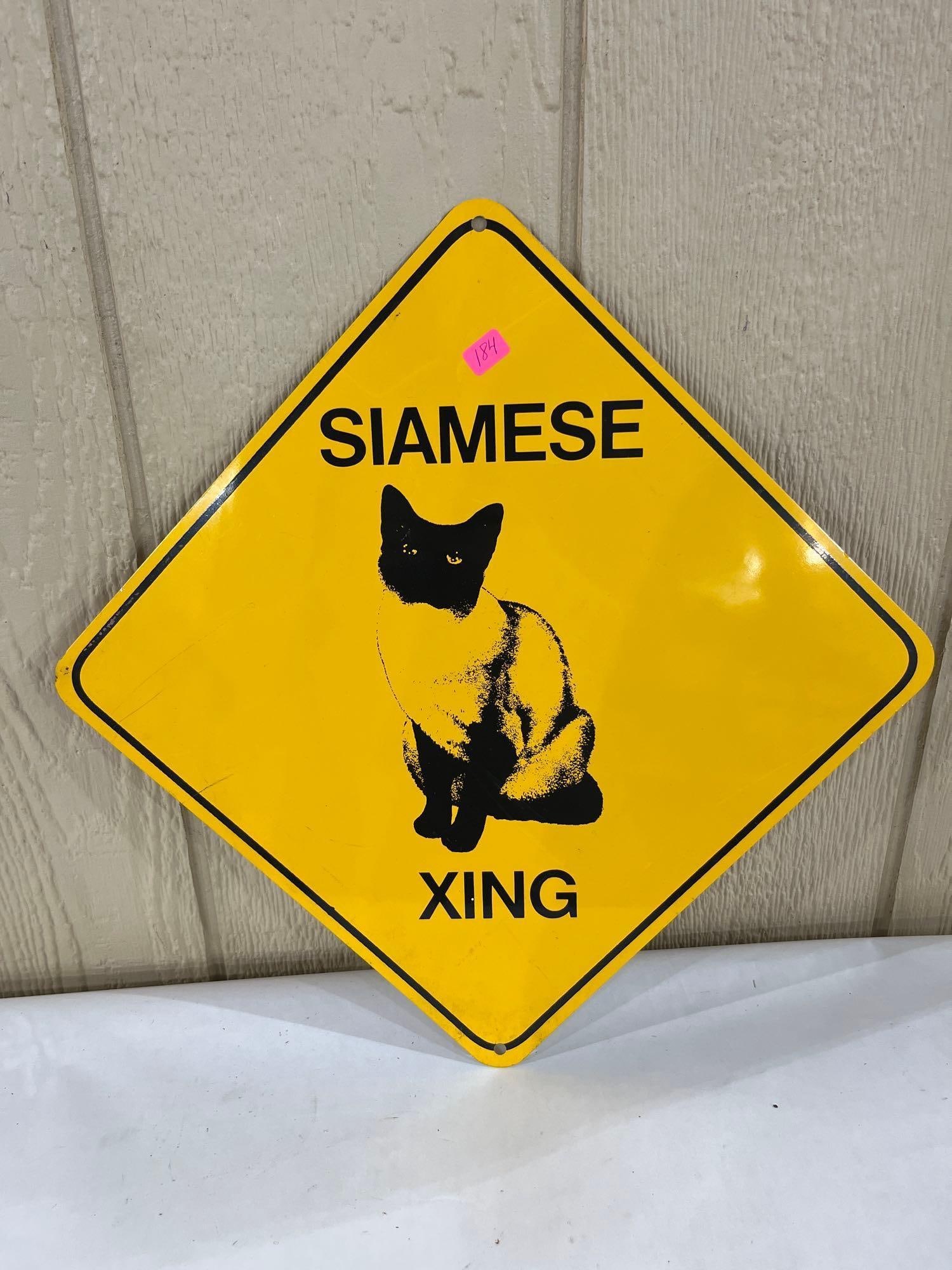 Siamese Cat XING Aluminum Novelty Crossing Sign: This diamond-shaped novelty sign, likely produced in the late 20th century, is constructed of painted aluminum. It features a bright yellow background with a black border. A high-contrast black