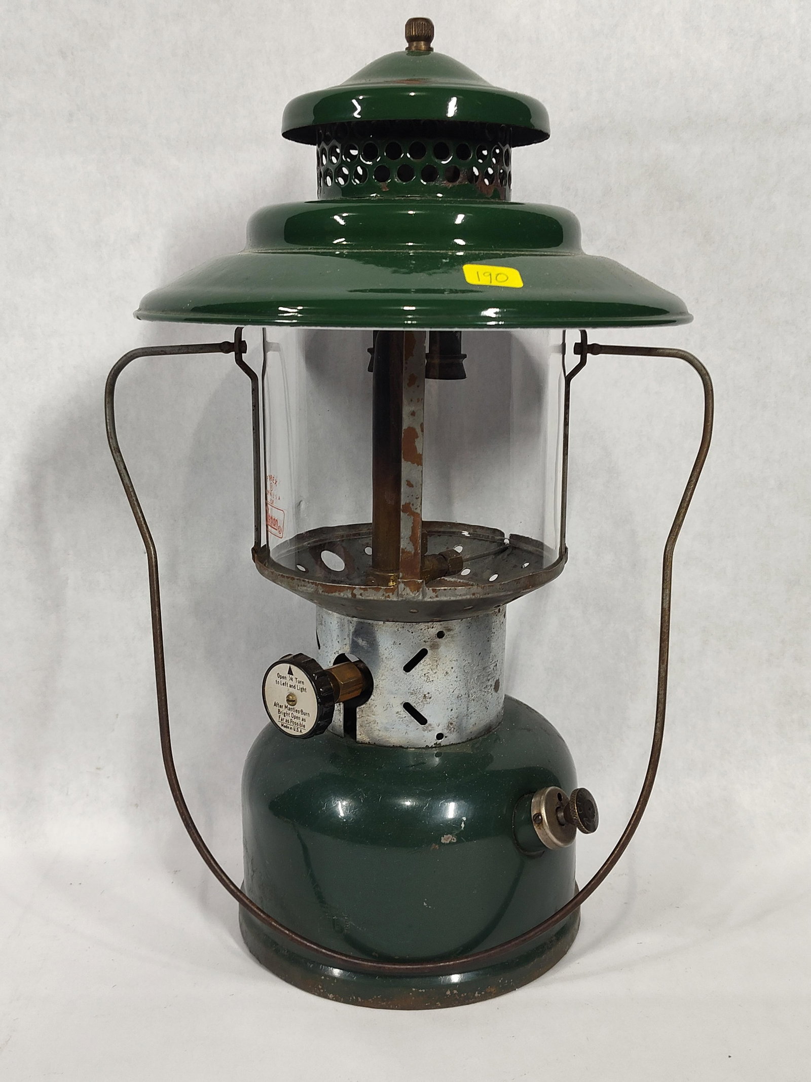 Vintage Coleman Model 228E Green Big Hat Lantern: A vintage Coleman Model 228E pressurized fuel lantern featuring a green painted metal fuel fount and a matching wide-brimmed, two-tiered green porcelain enamel ventilator. This model is commonly