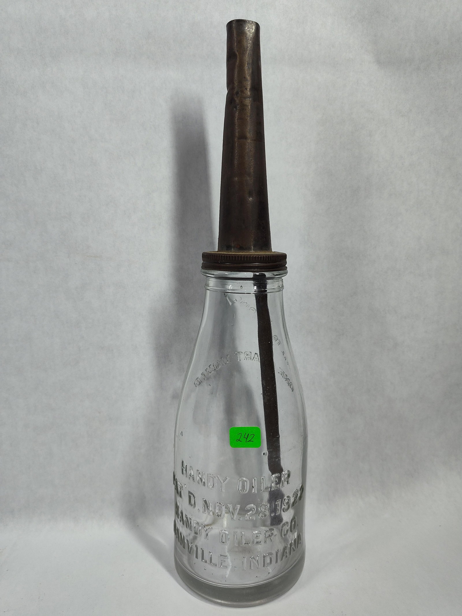 Vintage Handy Oiler Service Station Oil Bottle: Manufactured by the Handy Oiler Co. of Danville, Indiana, this vintage automotive lubricant dispenser consists of a clear glass vessel and a screw-on metal spout assembly. The bottle features a