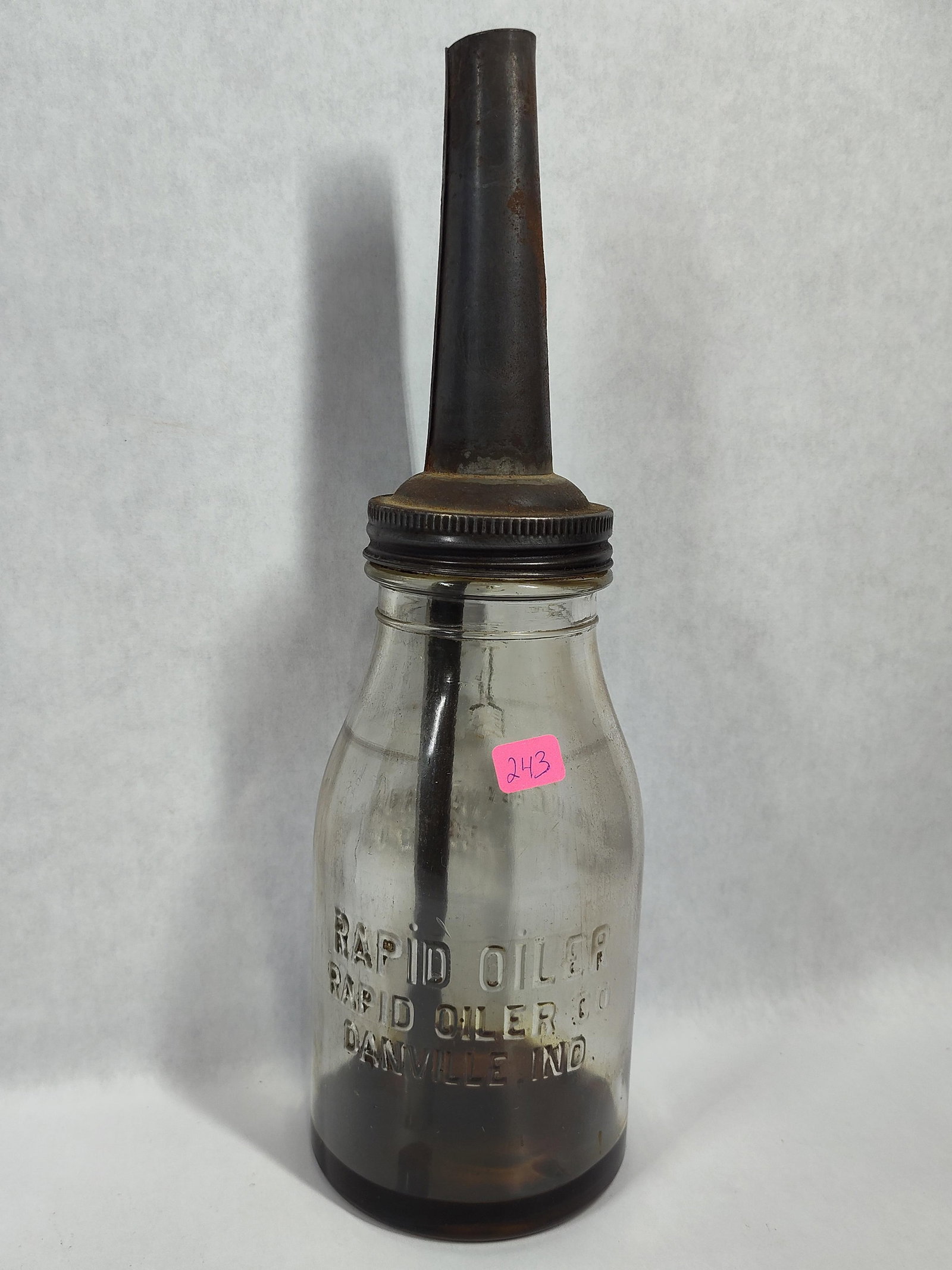 Rapid Oiler Co. Oil Bottle w/ Spout: This vintage motor oil service bottle was manufactured by the Rapid Oiler Co. of Danville, Indiana. The bottle is constructed of clear glass and is embossed on the front with the text RAPID OILER,