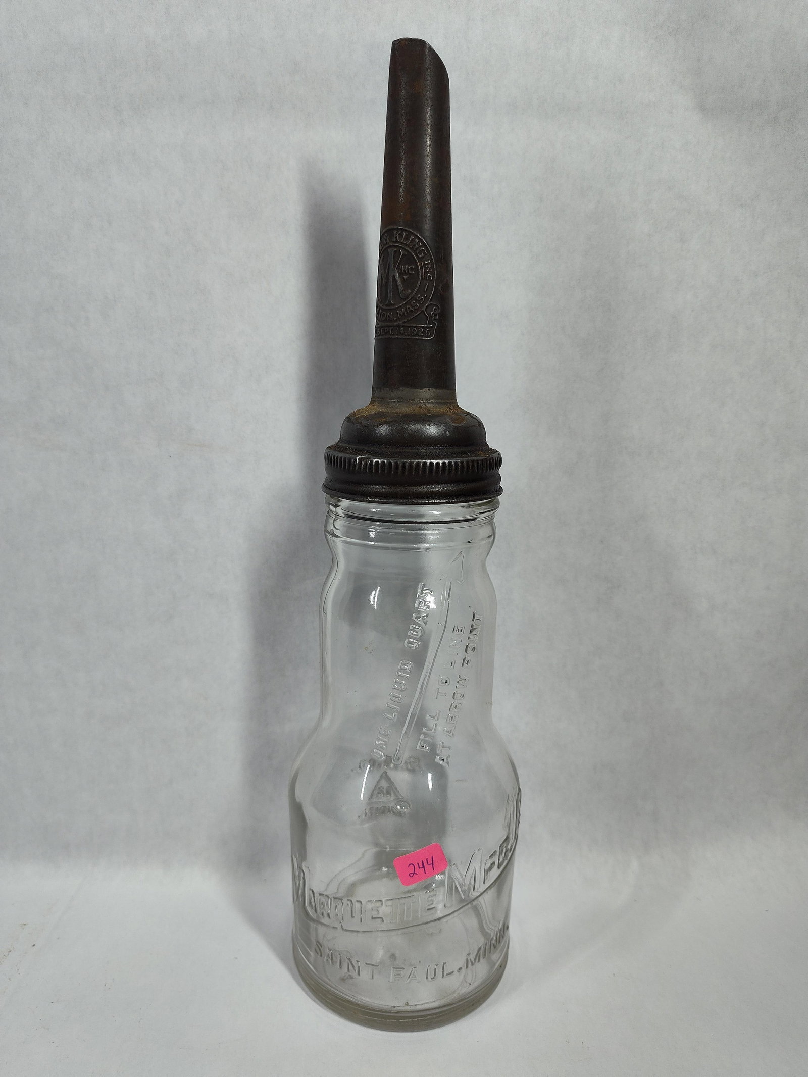 Marquette Glass Oil Bottle w/ Moore & Kling Spout: This antique liquid quart oil service bottle features a clear glass body manufactured by the Marquette Manufacturing Company of Saint Paul, Minnesota. The bottle is embossed with the company name and