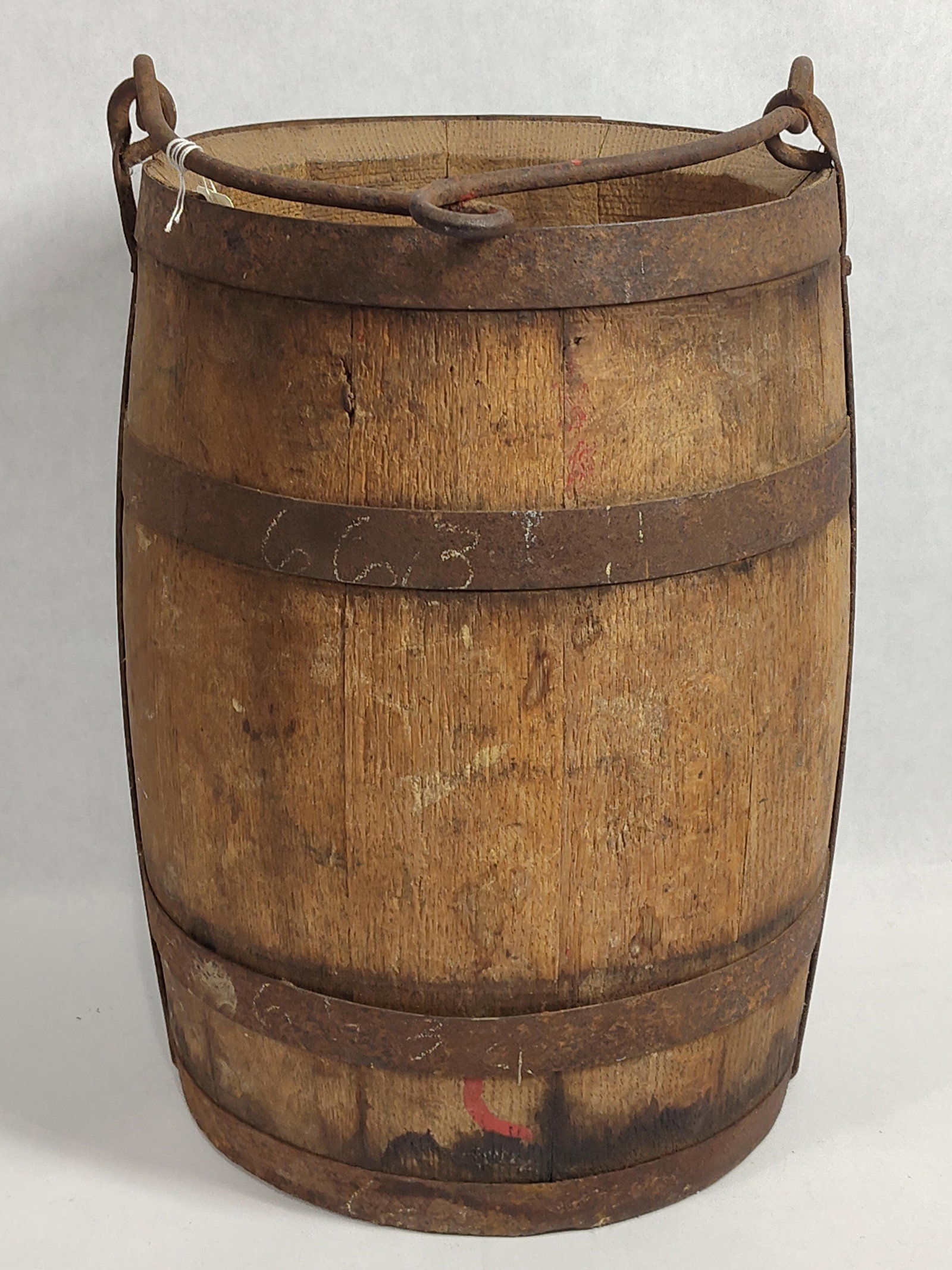 Wood Stave Well Bucket w/ Iron Hoops & Bail Handle: An antique well bucket featuring traditional stave construction. The body consists of vertical wooden staves secured by three horizontal iron hoops. Two vertical metal side straps reinforce the