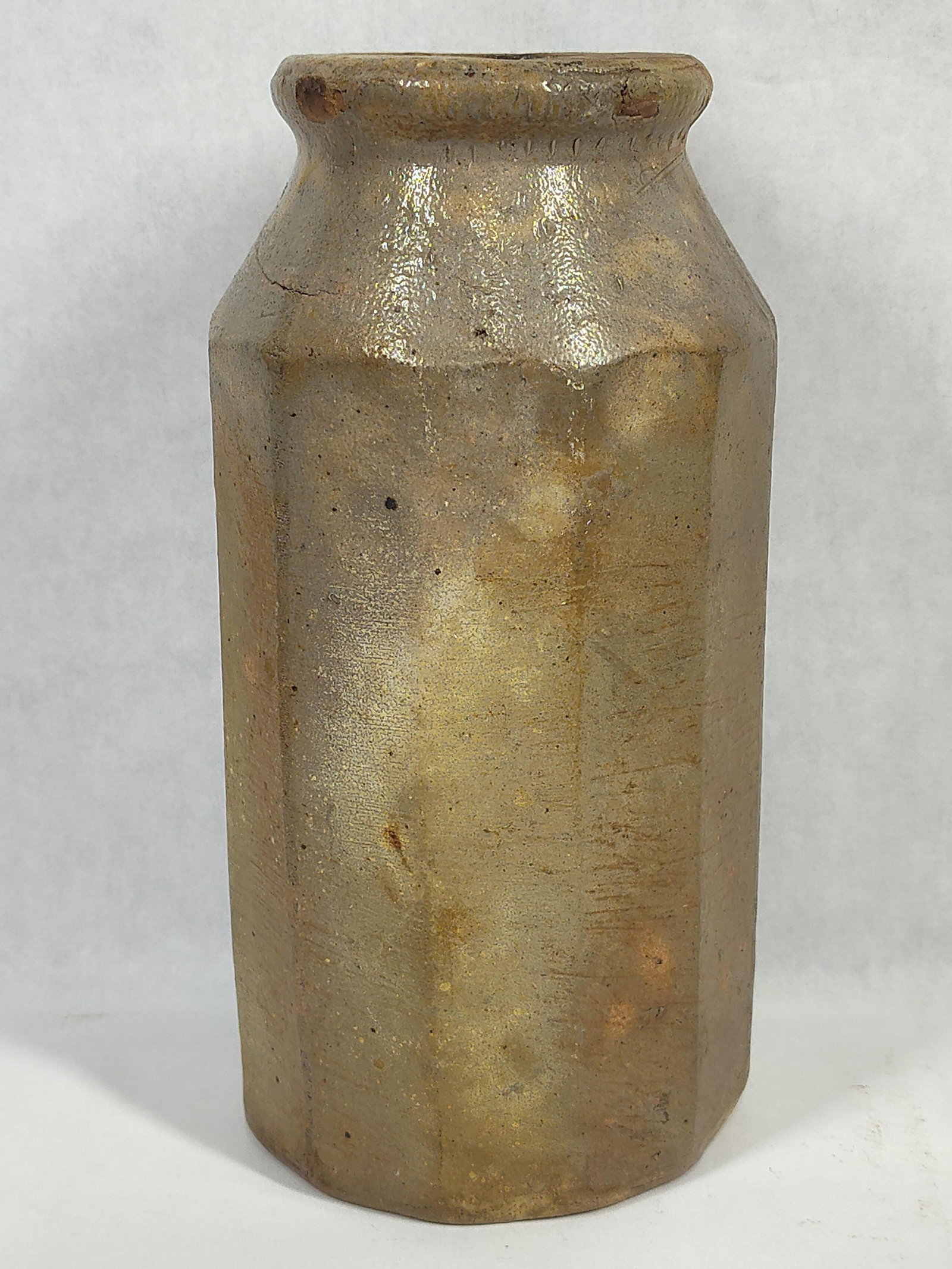 Salt-Glazed Octagonal Stoneware Master Ink Bottle: This is an antique salt-glazed stoneware bottle with an eight-sided octagonal body. The vessel features faceted sides that transition into sloped shoulders and a short neck ending in a thick,