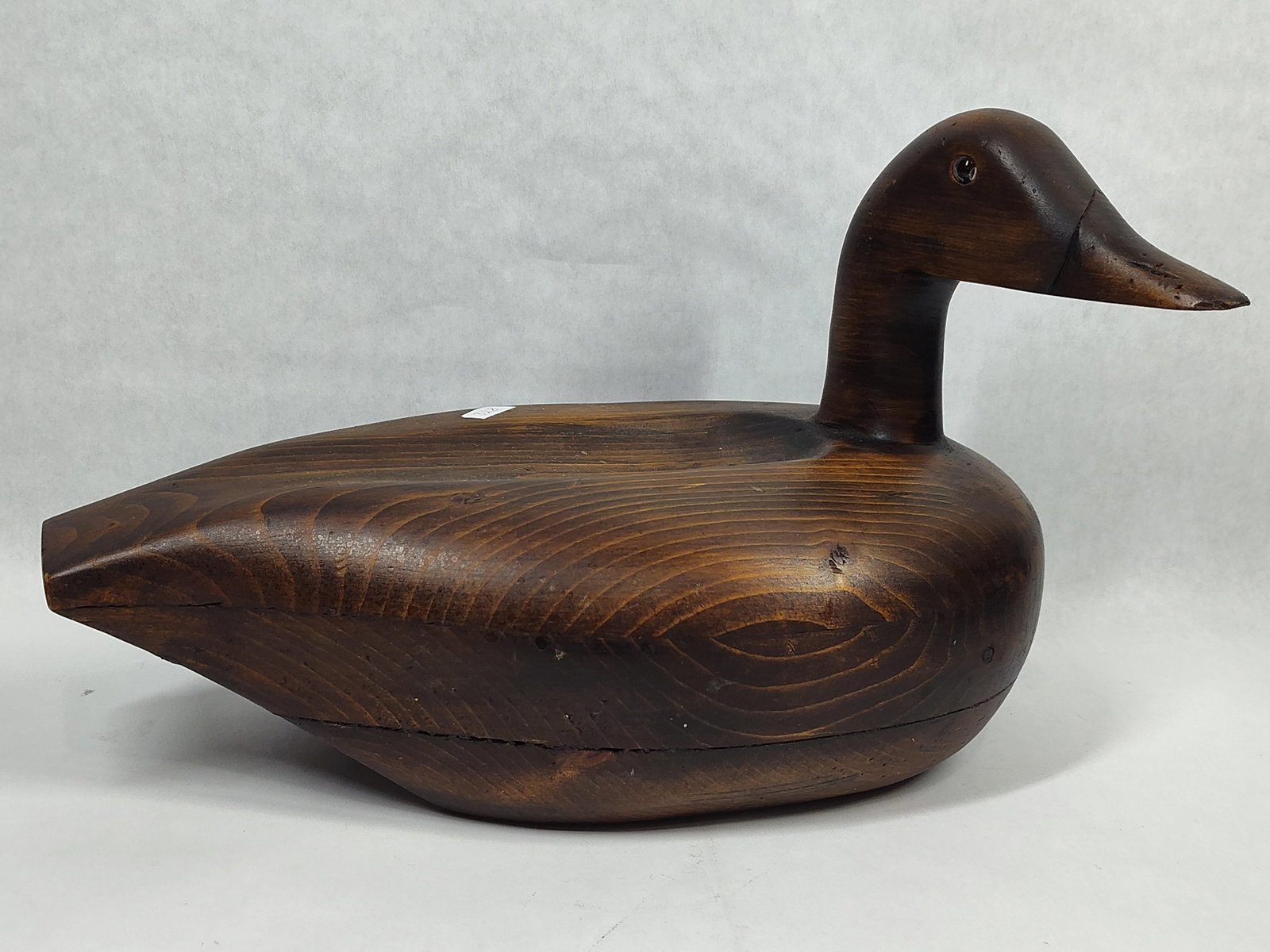 Carved Wood Duck Decoy, Trapshooting Hall of Fame: This vintage hand-carved duck decoy is constructed from wood with a dark brown stained finish that highlights the underlying grain. The item is built in multiple sections, featuring a visible