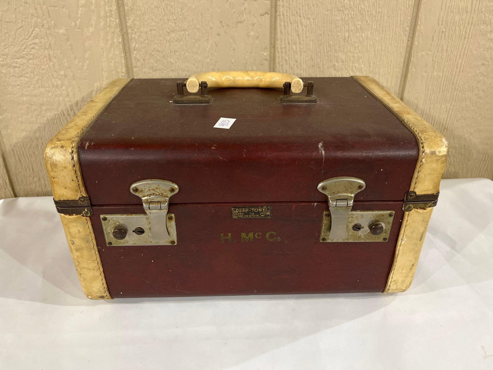 Vintage Deep-Tones by Crown Maroon Train Case: This vintage vanity train case features a maroon textured exterior, likely faux leather or vinyl, with contrasting cream-toned reinforced edge binding and a curved, light-colored plastic handle. The