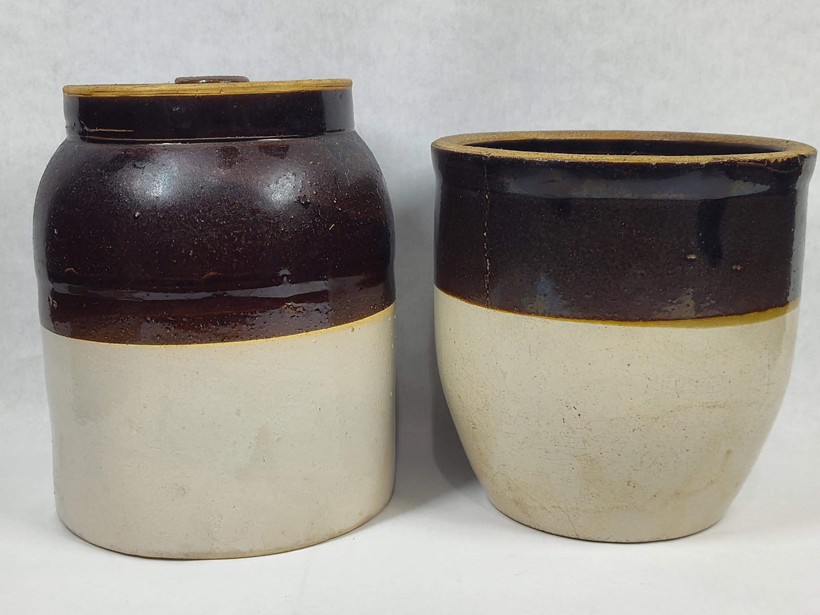 Pair American Two-Tone Stoneware Jar & Crock: This lot features two pieces of American utilitarian stoneware characterized by a traditional two-tone glaze. The first vessel is a cylindrical storage jar designed with a rounded shoulder and a