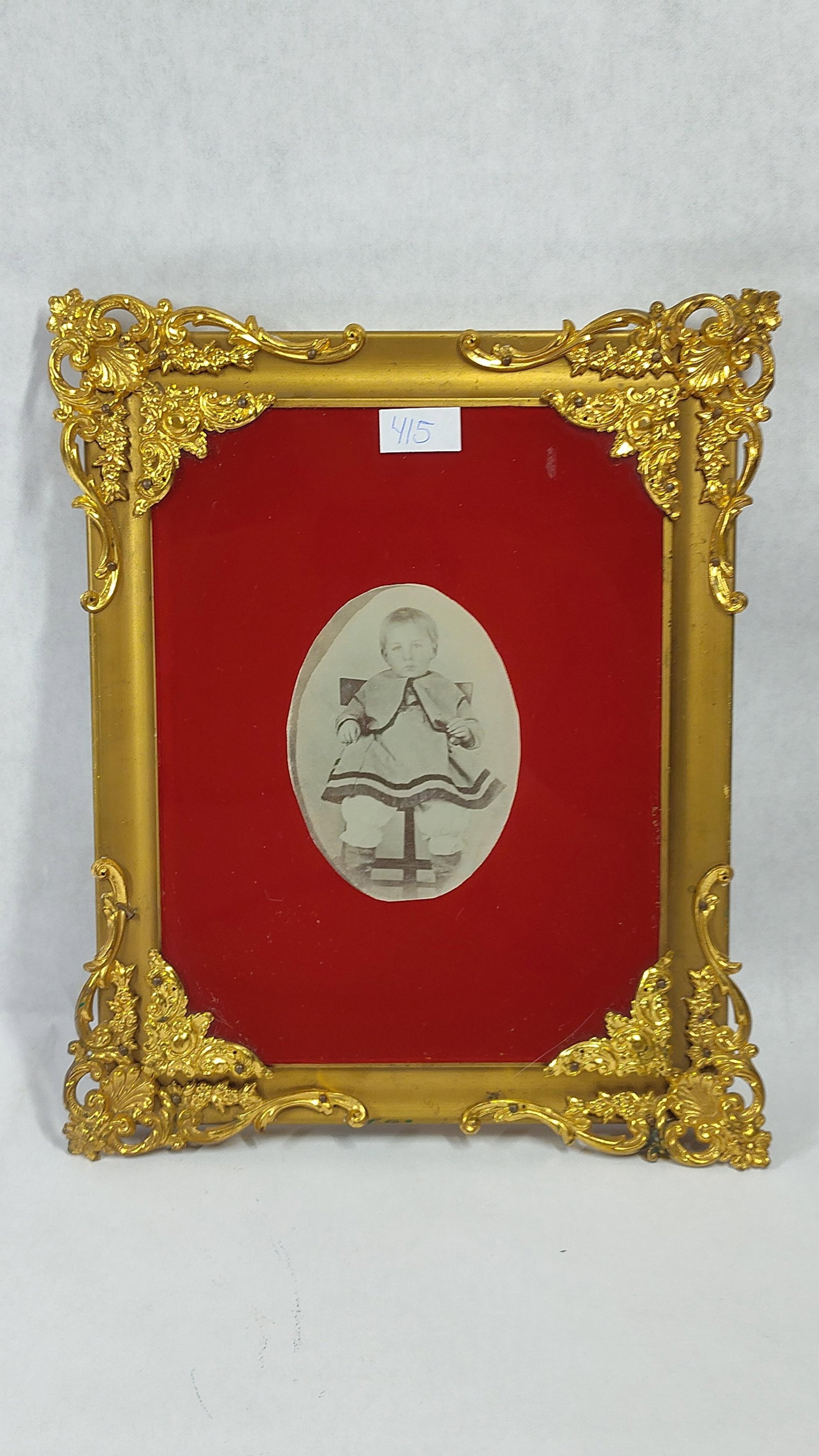 Silver Gelatin Child Portrait, Gilt & Velvet Frame: This studio portrait consists of a vintage silver gelatin print depicting a young child seated on a high stool. The child is dressed in period attire, including a dark tunic with a cape collar and
