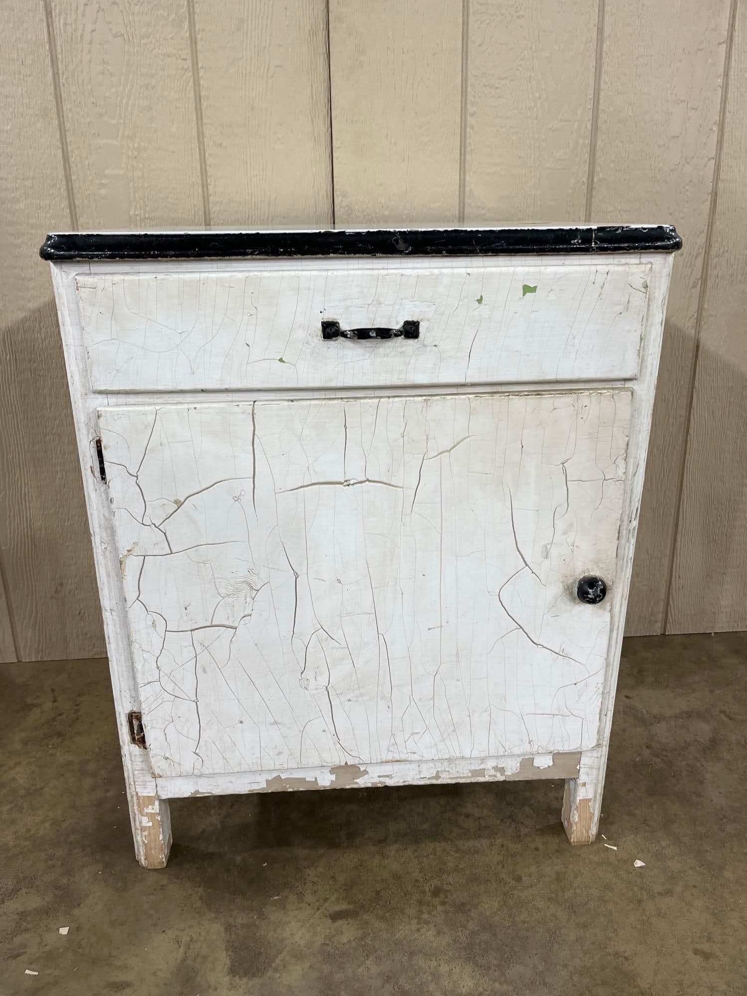 Antique White Utility Cabinet w/ Porc. Enamel Top: This is a single-piece early 20th-century American utilitarian cabinet, commonly used as a washstand or small kitchen workstation. The piece is constructed with a wooden frame finished in white paint 