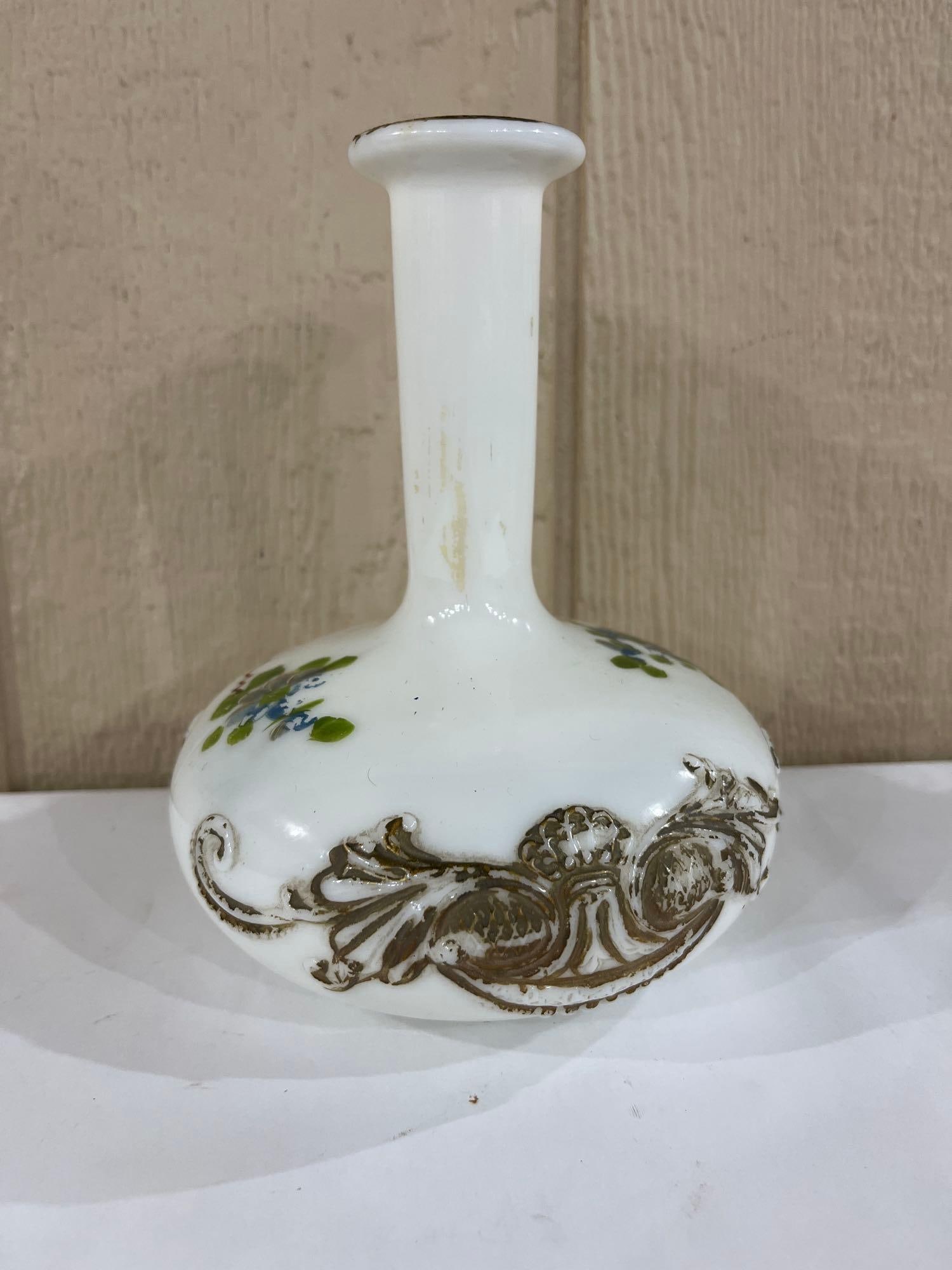 Victorian Hand-Painted Milk Glass Gilt Relief Vase: This Victorian era miniature vase is crafted from opaque white opal glass, commonly known as milk glass. The piece features a bulbous body that tapers into a slender, elongated neck with a flared rim.